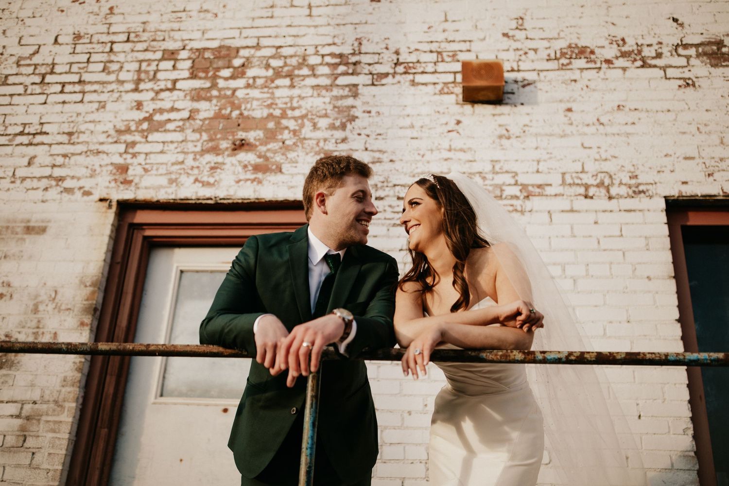 Romantic wedding portraits against white painted brick wall background.
