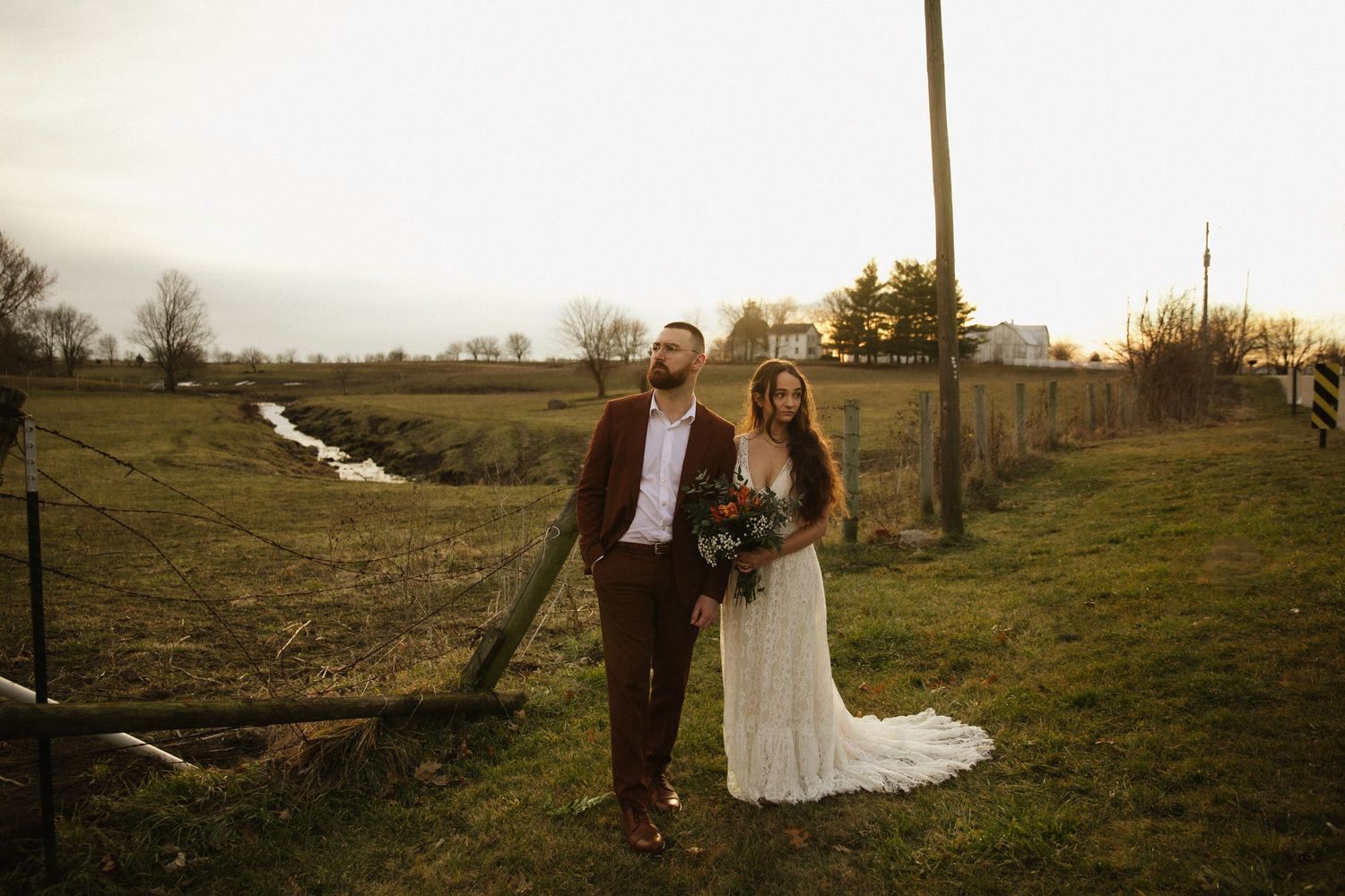 Scenic wedding photos taken in a pastoral landscape at sunset.