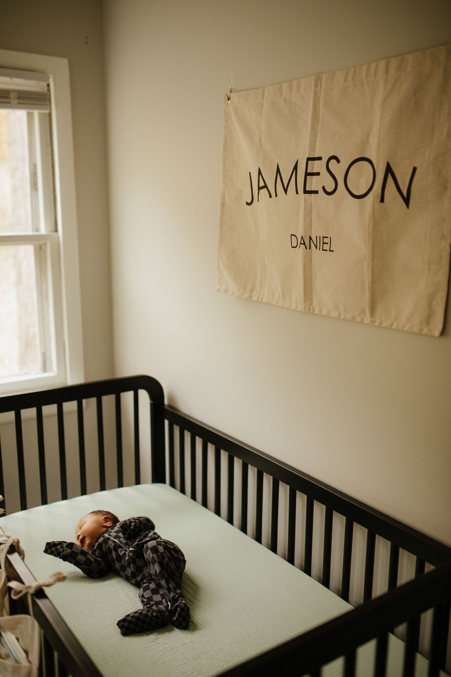 A nursery room with a crib and name banners reading 'Jameson' and 'Daniel' on the wall.