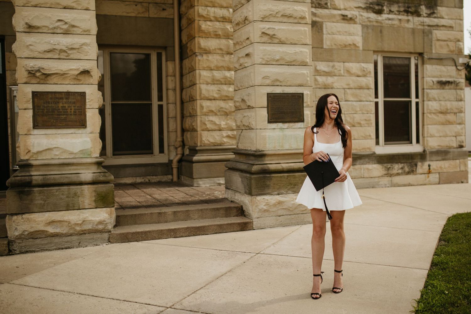 An elegant portrait in front of a historic limestone building with classical architecture.