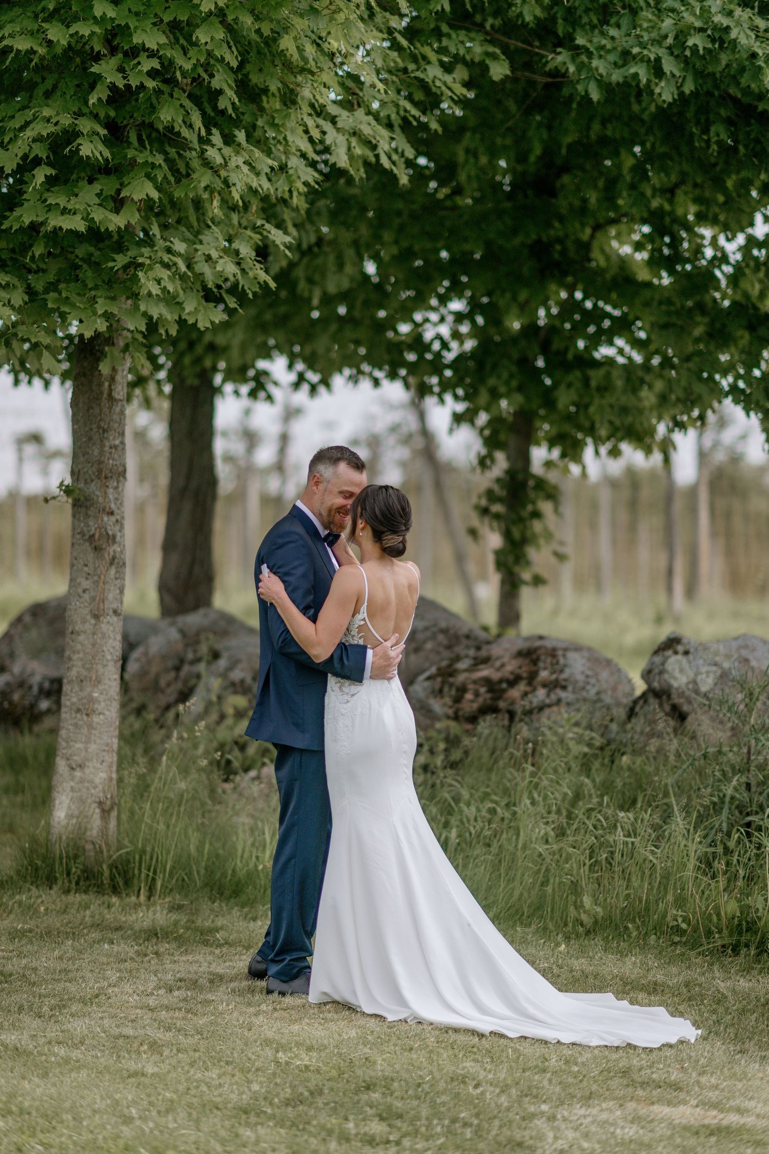 Intimate wedding portraits taken in a peaceful garden setting with tall trees.