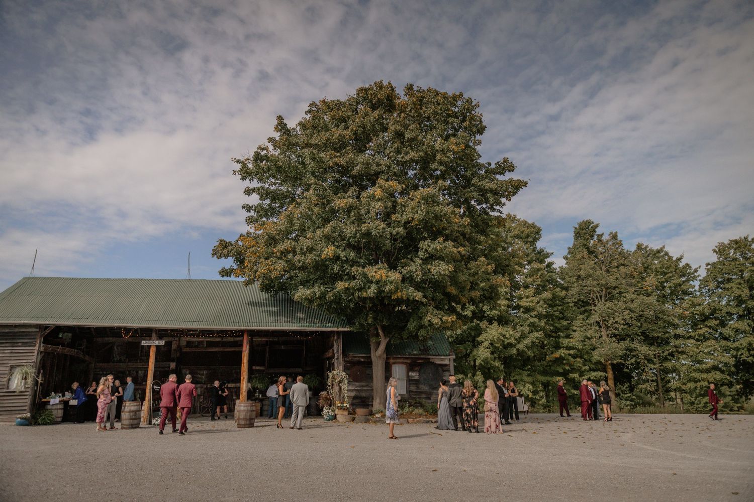 Panoramic view of a rustic barn wedding venue with guests arriving.