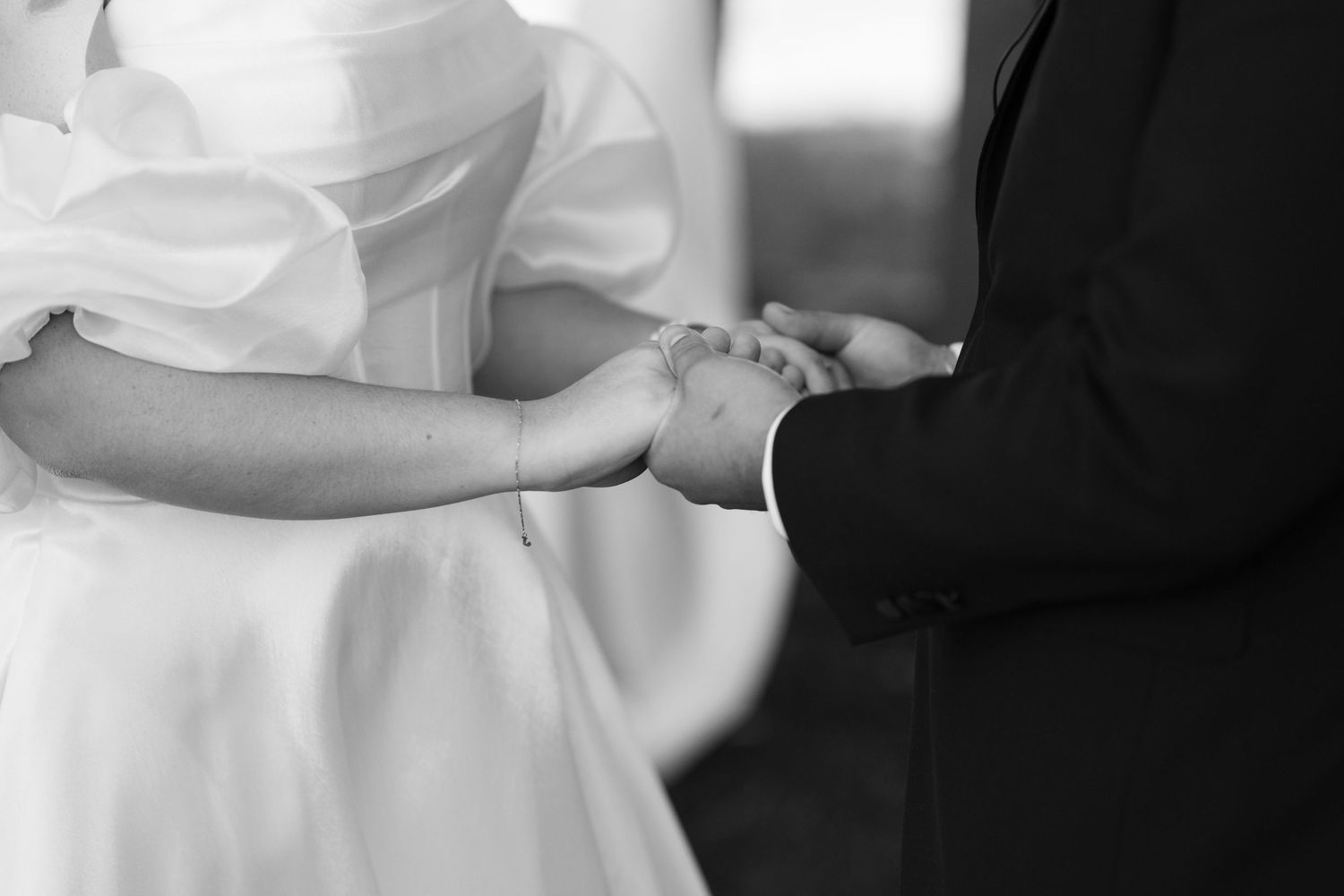 Black and white photograph shows hands holding and interacting with a mobile phone or digital device.
