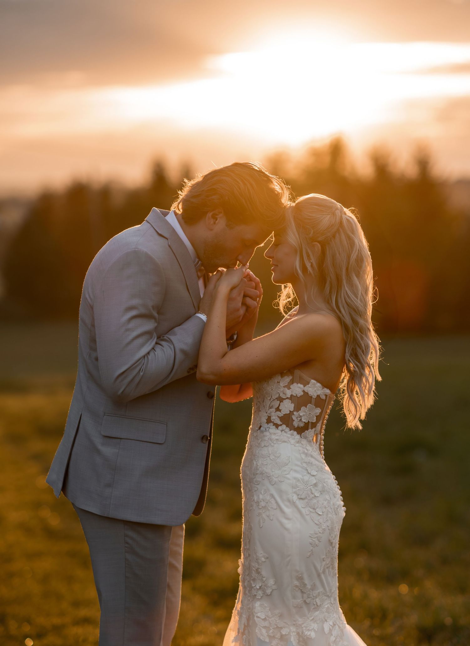 Bride and groom share a romantic sunset moment in a golden field, her lace gown glowing as they lean in close.