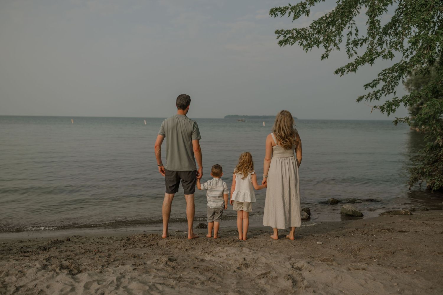 Family standing together on a beach shoreline during golden hour.