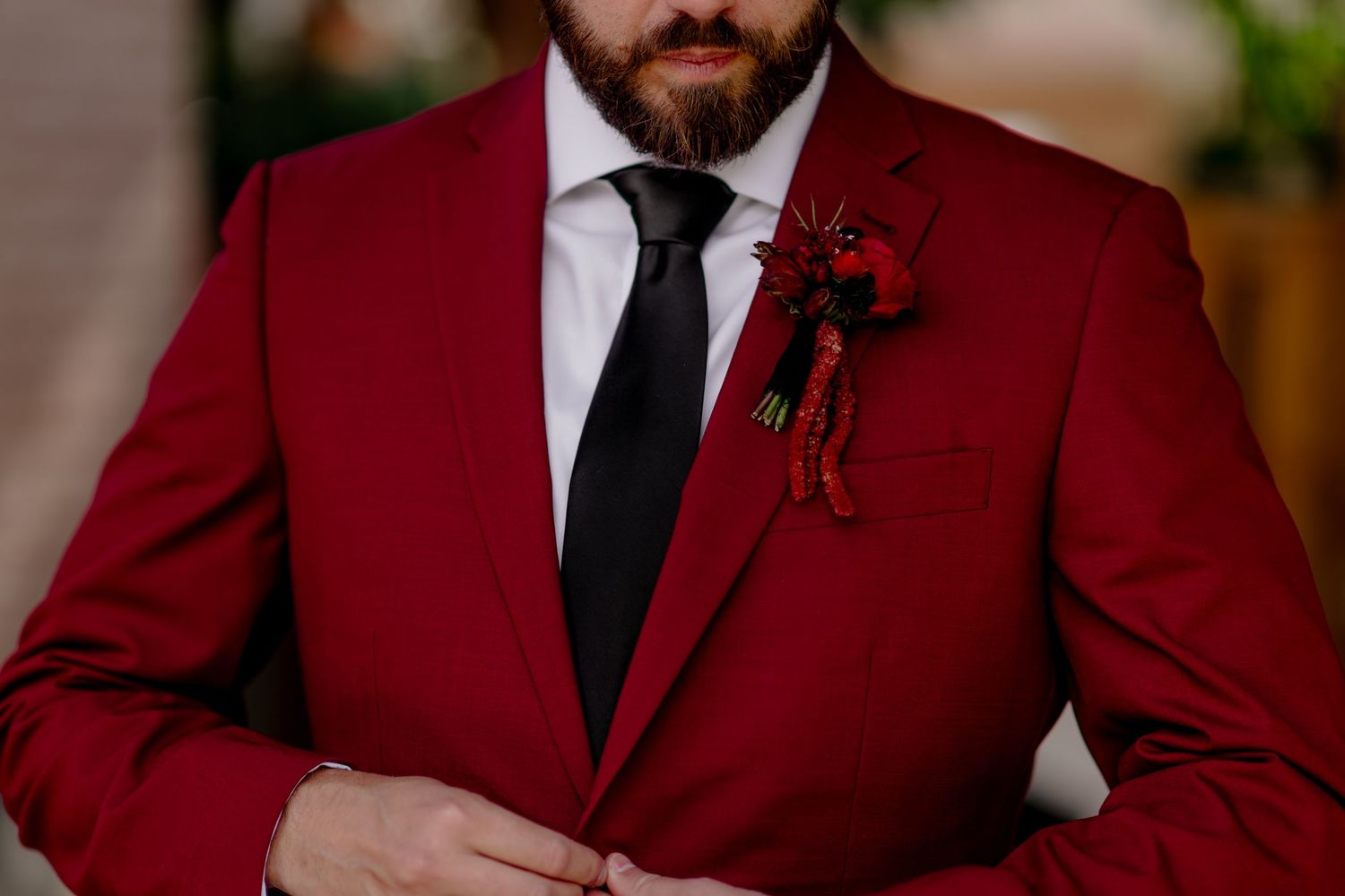 Groomsmen wearing matching burgundy suits with black ties stand together for a formal wedding photo.