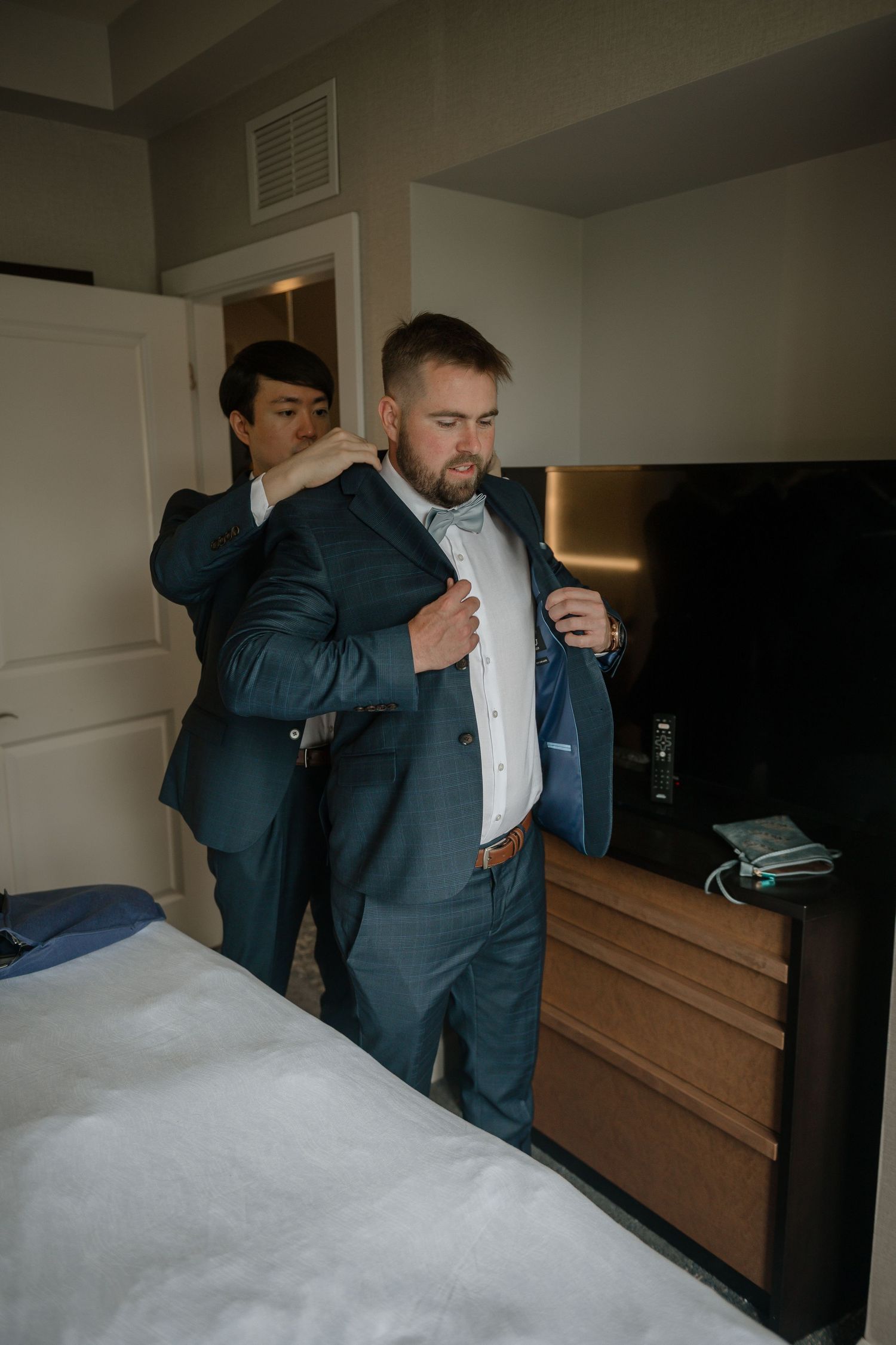 A series of shots showing someone adjusting a navy blue suit jacket and white dress shirt in preparation for a formal event.