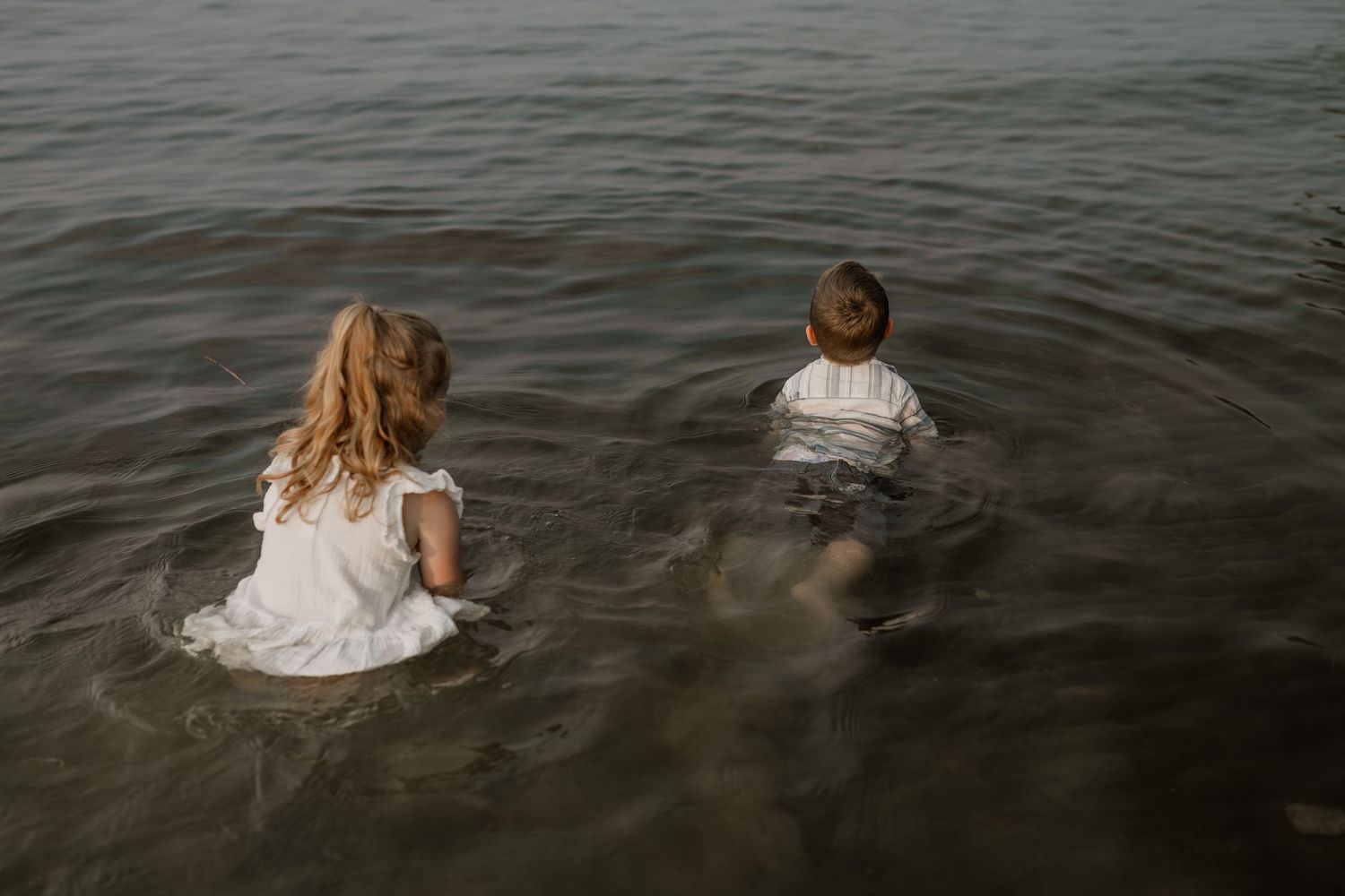 People wading in dark water during a moody beach photoshoot.
