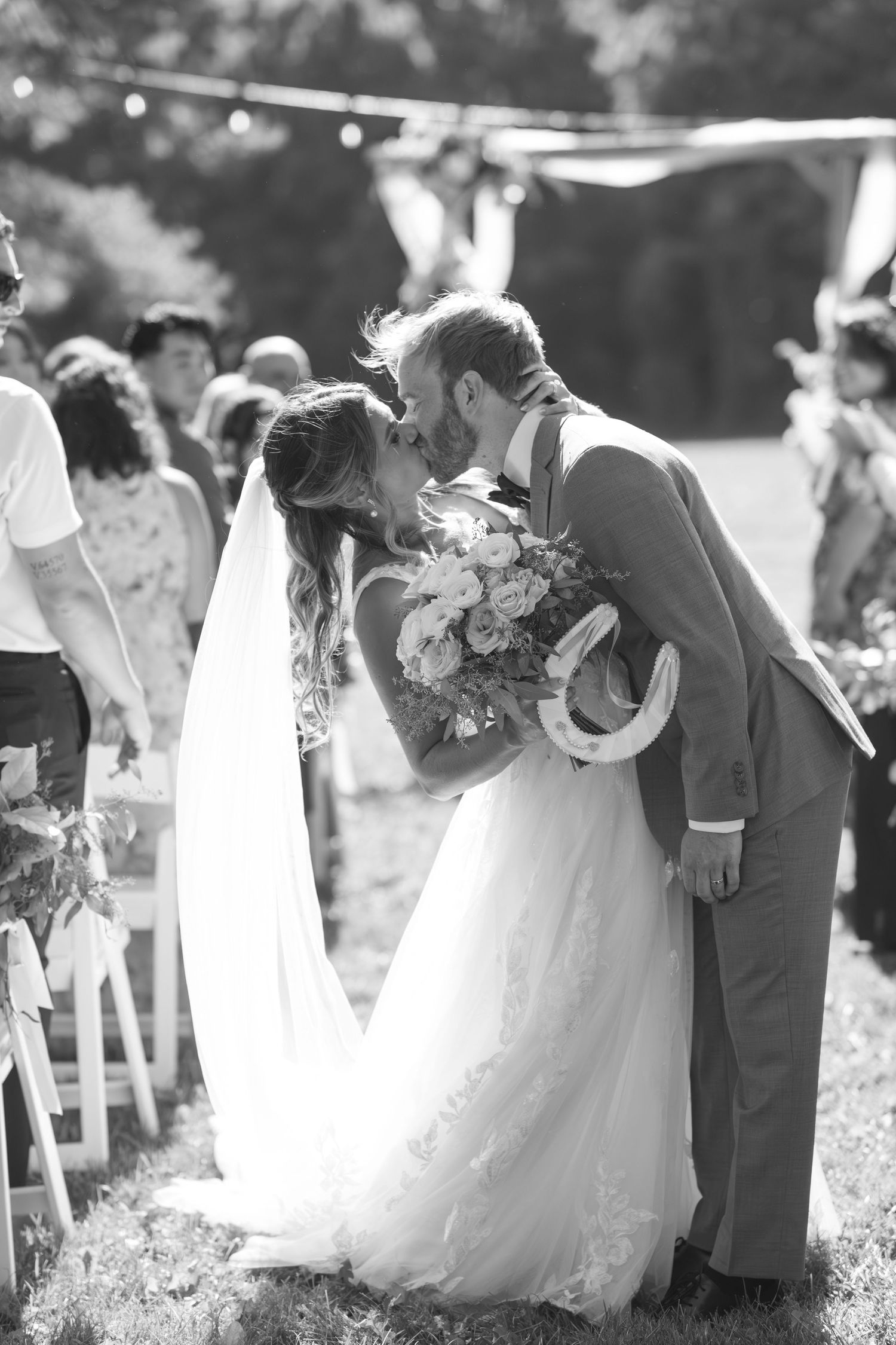 A romantic wedding ceremony moment captured in black and white with a couple sharing a kiss at the altar.
