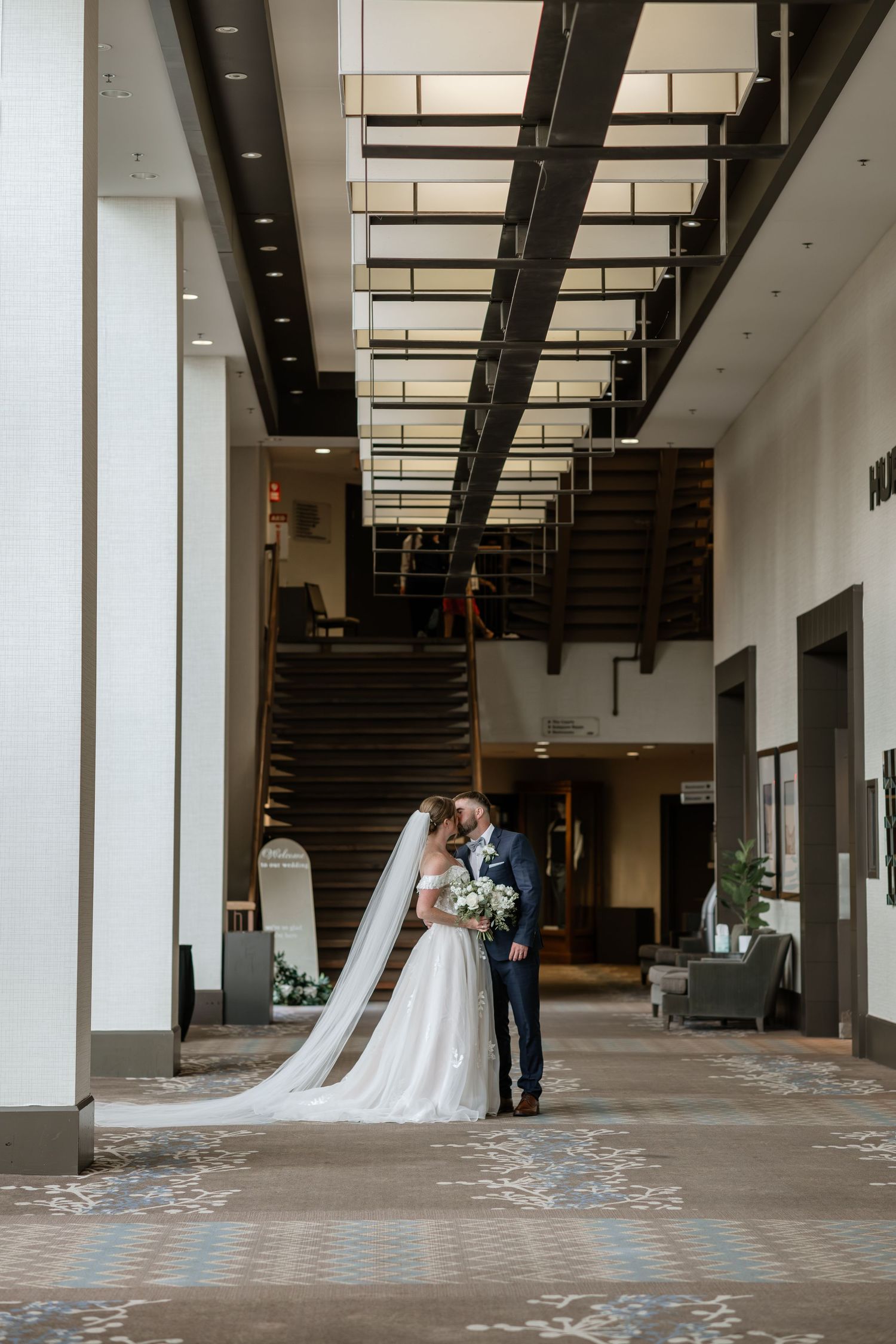 Elegant wedding ceremony setup in a modern indoor venue with white columns and natural lighting.