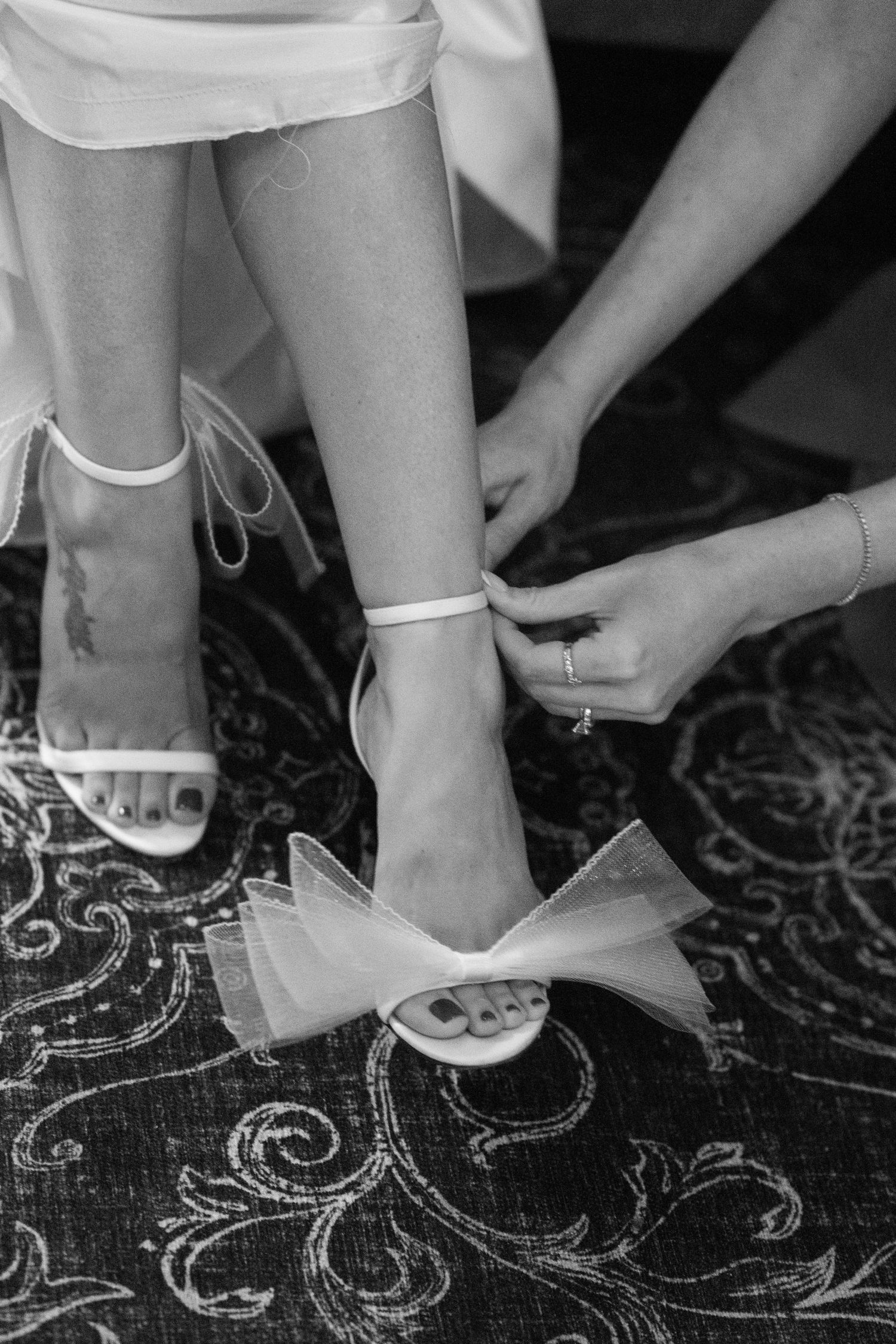 Close-up of elegant white bridal shoes on a decorative patterned floor.