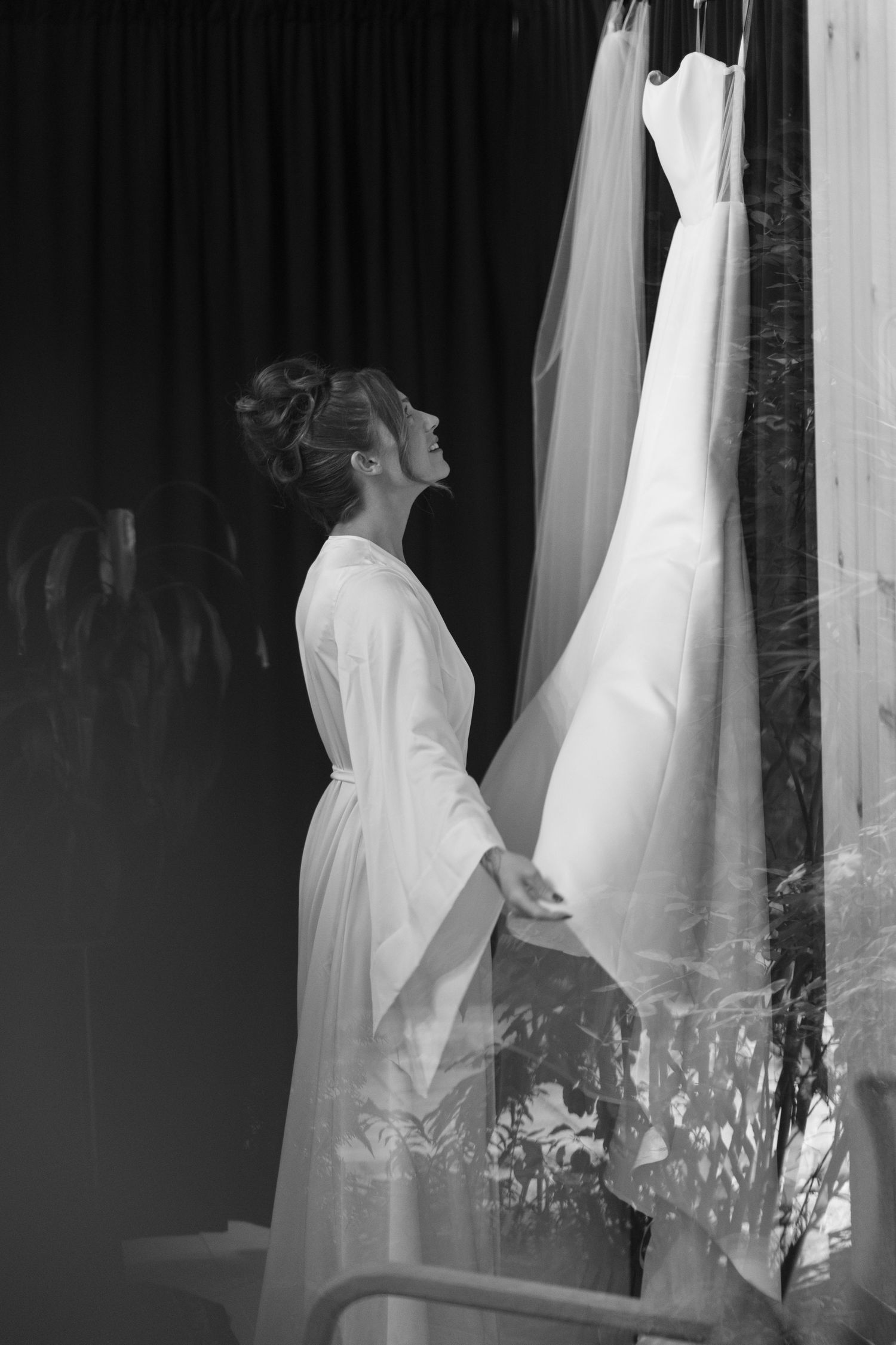 Wedding dresses hanging in a row creating an artistic silhouette against a dark background.