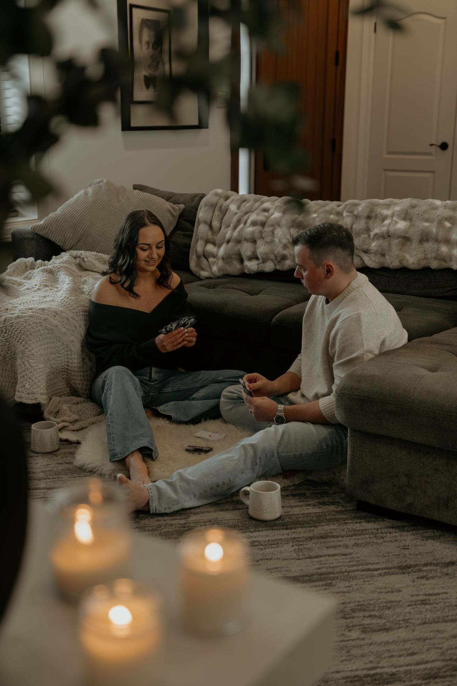 Cozy indoor scene with candles and couple relaxing on sofa.