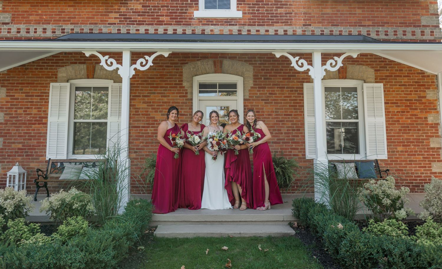 Exterior view of a red brick house with white porch columns and decorative trim.