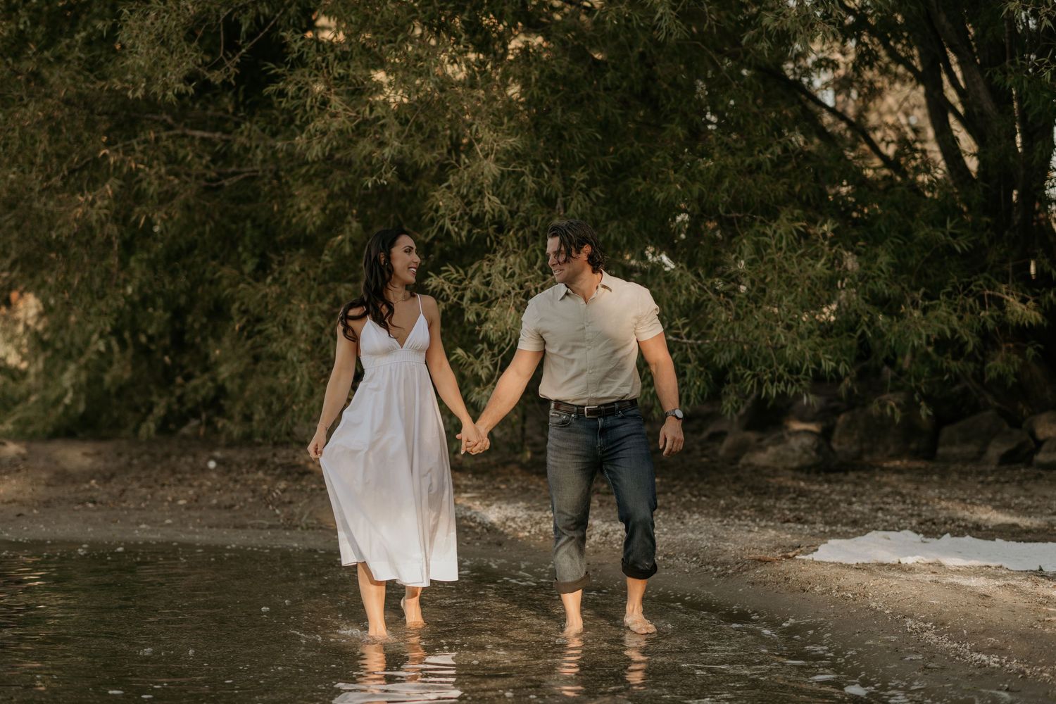 A couple walking hand in hand through a scenic outdoor setting wearing casual summer attire.