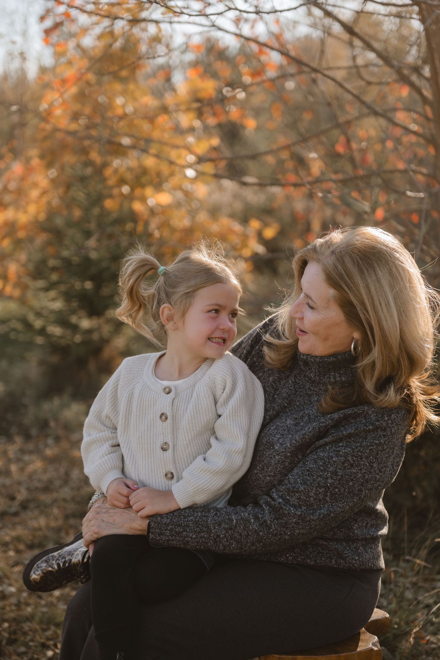 Family members cuddle and laugh together on a cozy blanket during fall photo session.