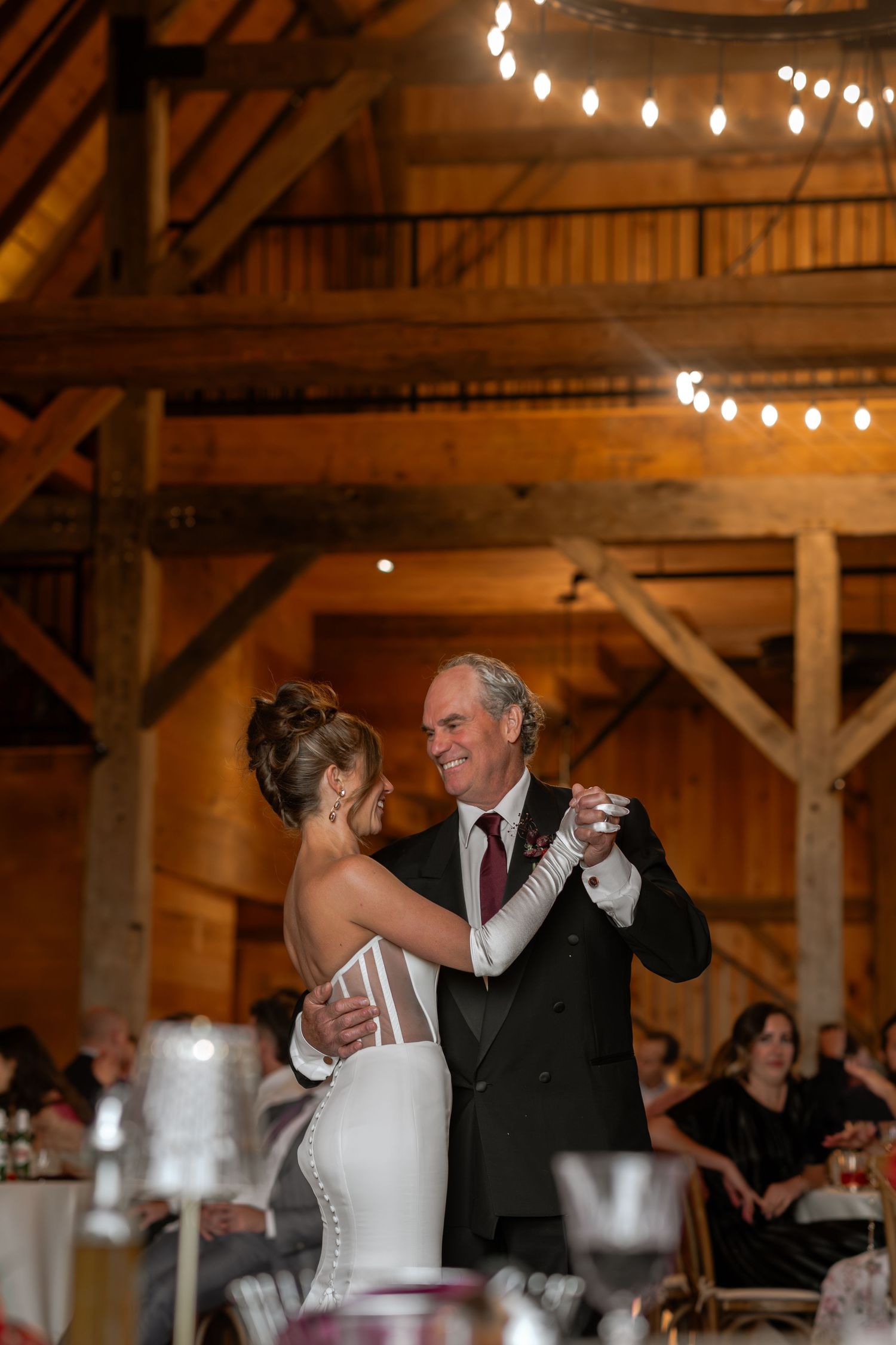 Intimate first dance moment in a rustic barn venue with string lights overhead.