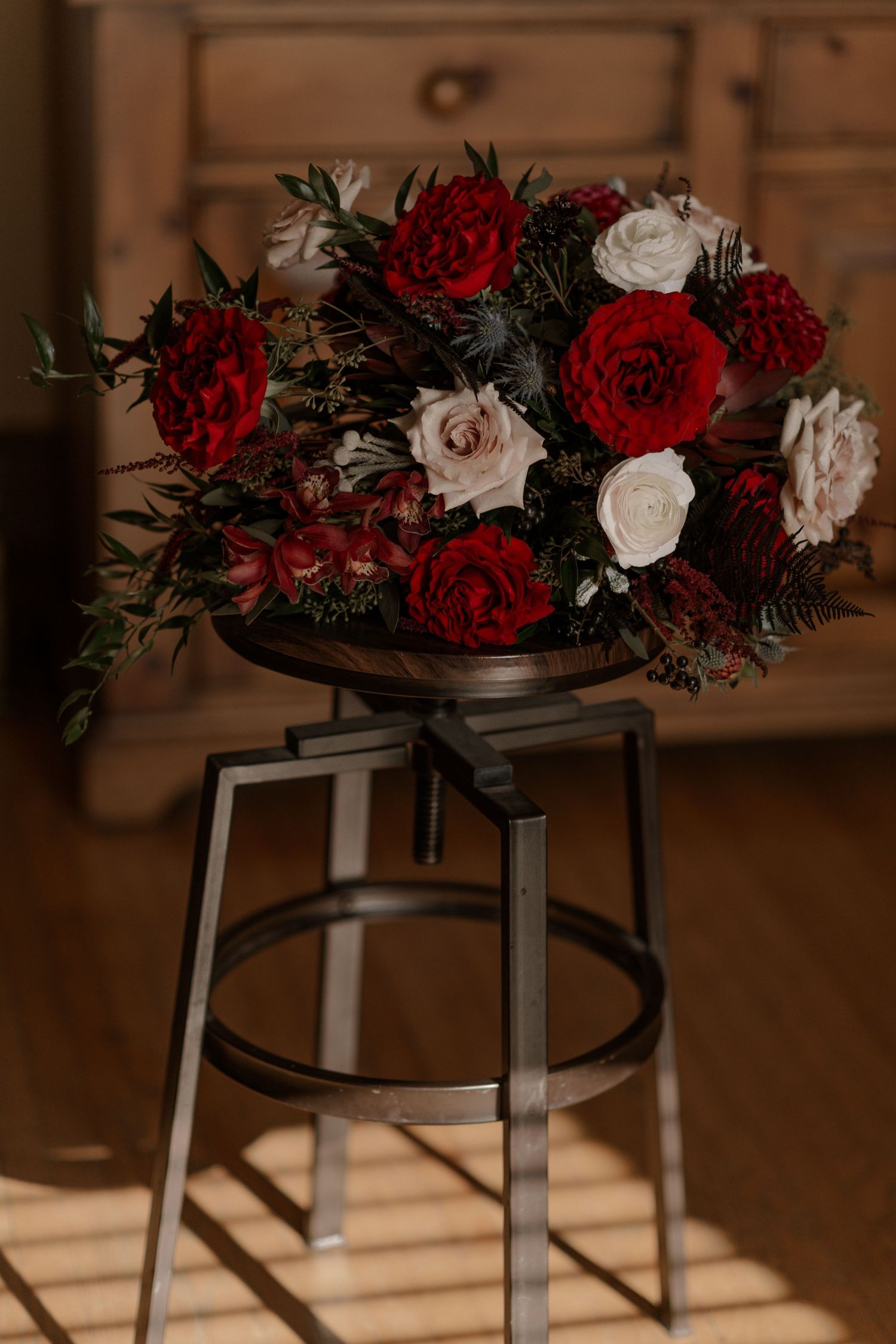 Elegant floral arrangements with deep red and white roses displayed on black metal stands.