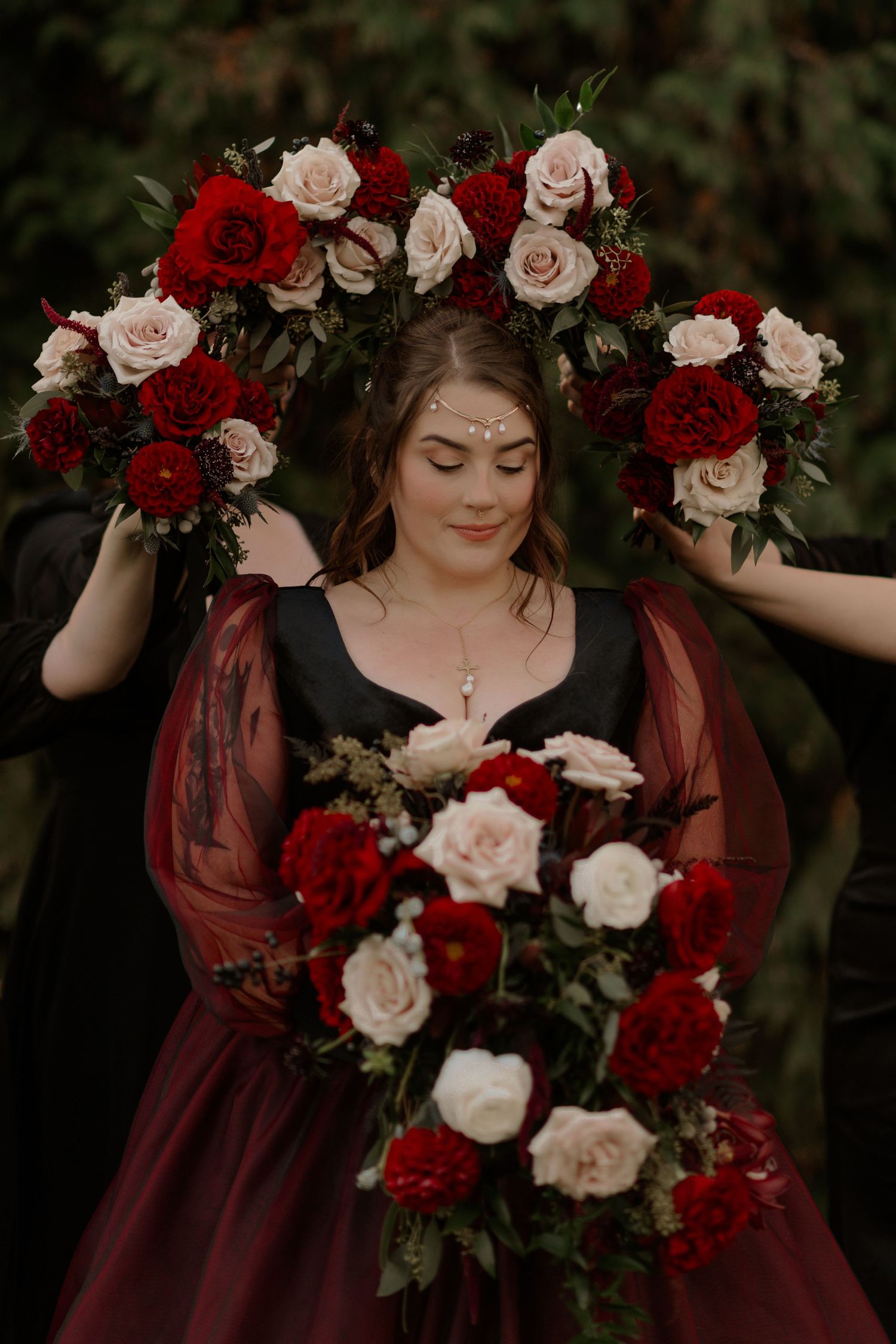A romantic floral arrangement with red and pink roses frames a person in a burgundy dress.