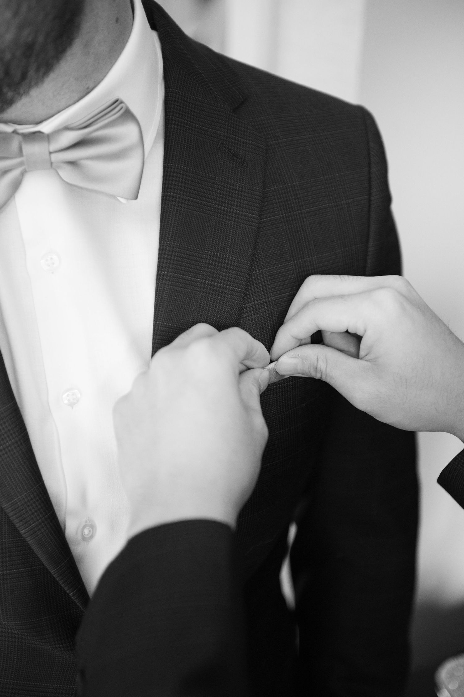 Close-up shots of hands adjusting a white dress shirt collar and suit jacket lapels.