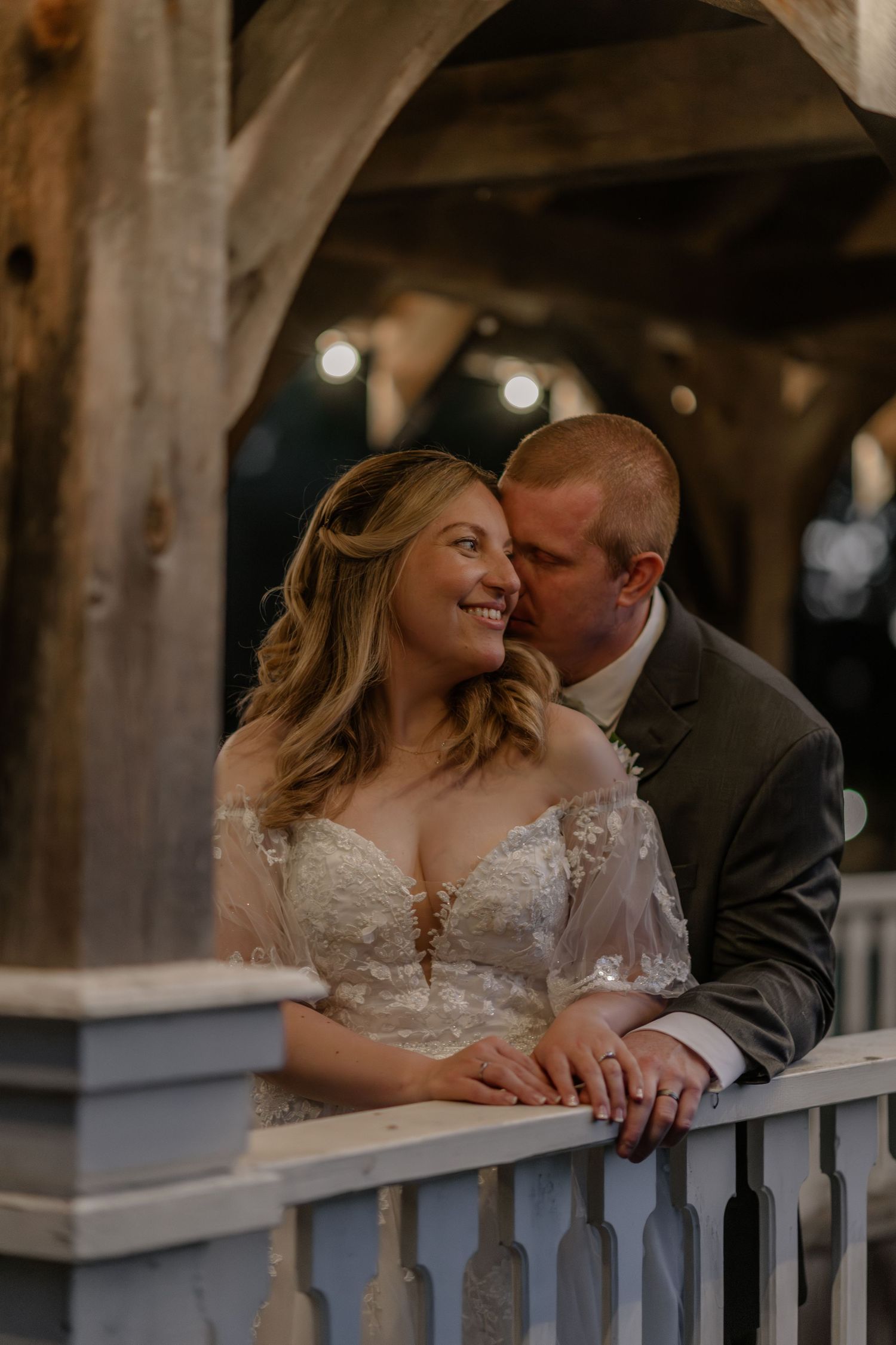 Intimate wedding couple moment on a rustic wooden balcony with soft lighting.