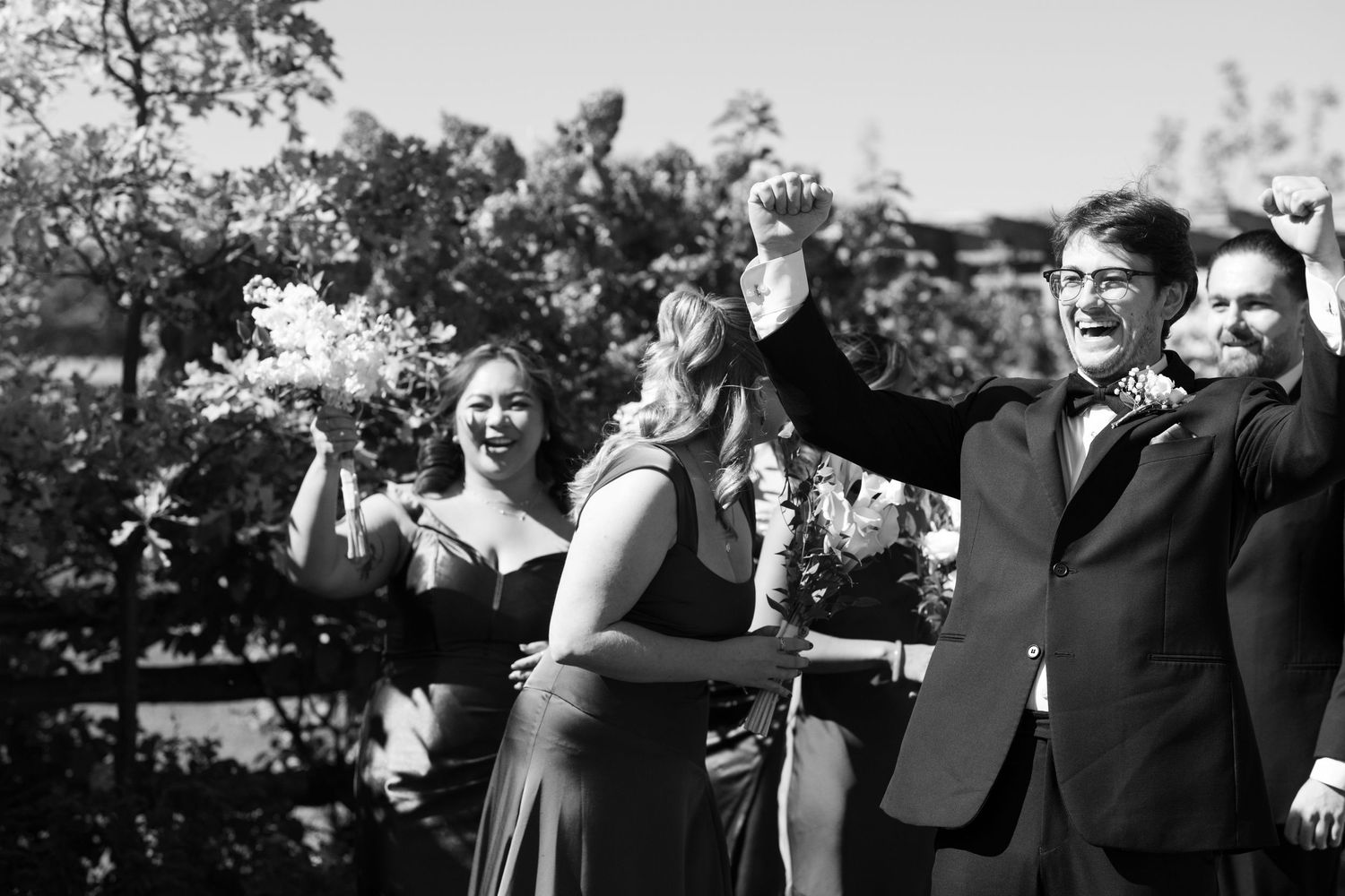 A joyous celebration captured in black and white as people raise their arms in excitement at an outdoor gathering.