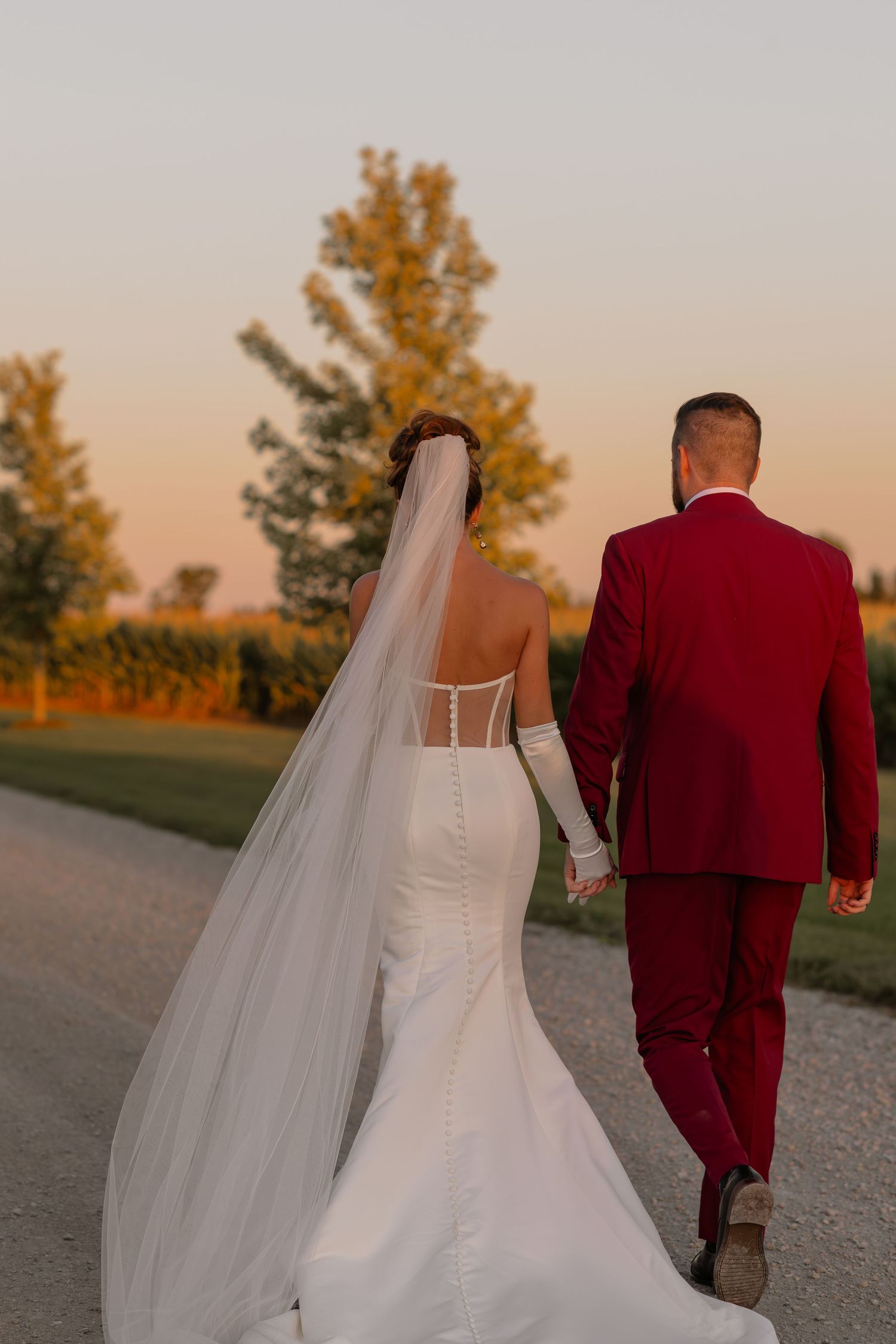 Sunset silhouette of a couple in wedding attire walking away on a path together.