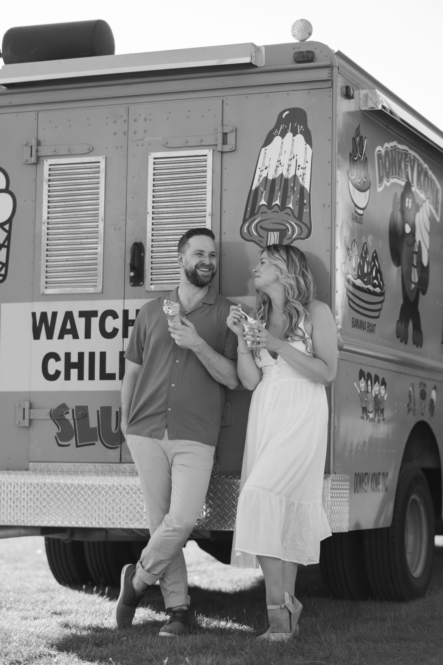 Black and white photo of couple laughing together near a food truck.