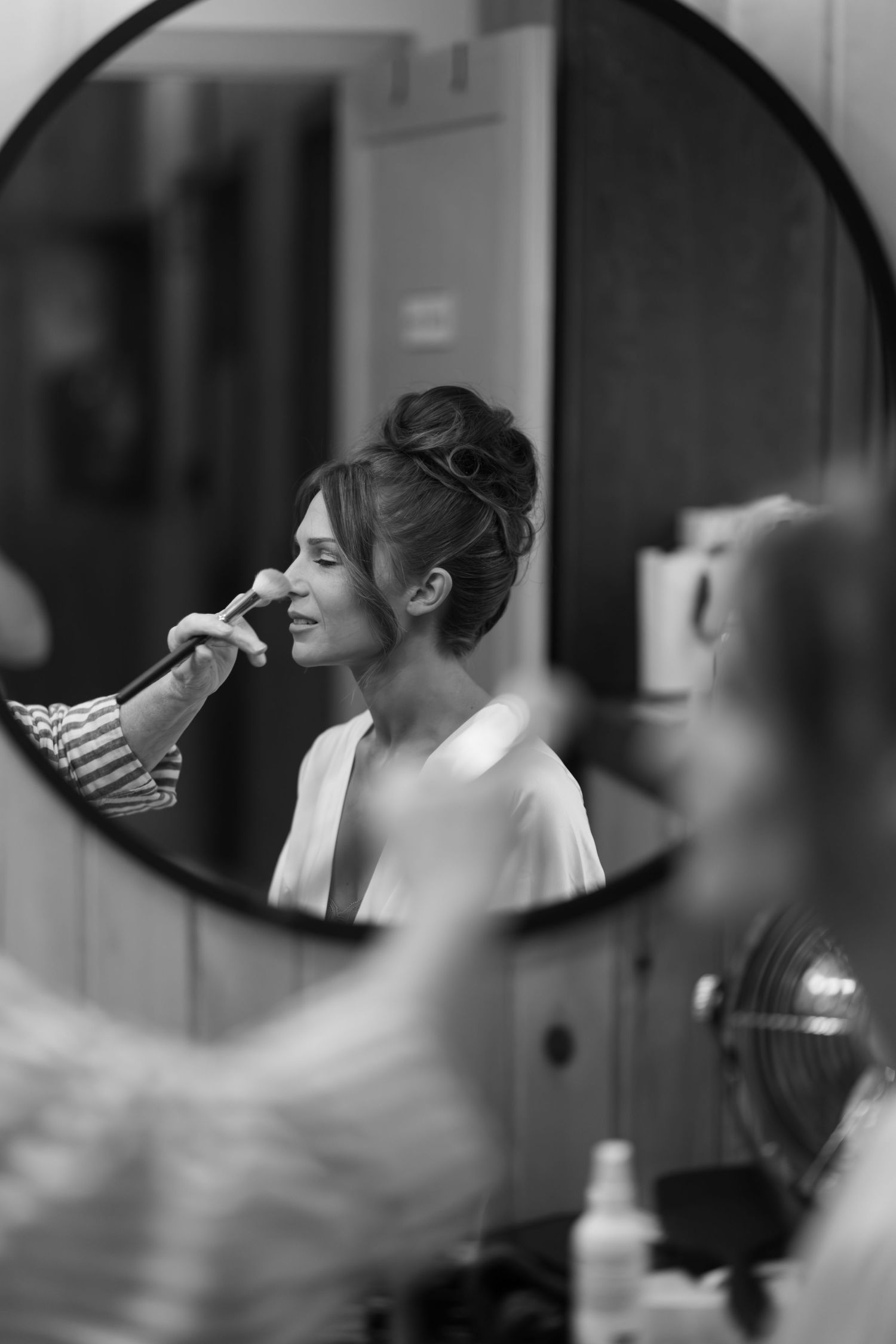 Black and white reflection in mirror of bridal makeup preparation.