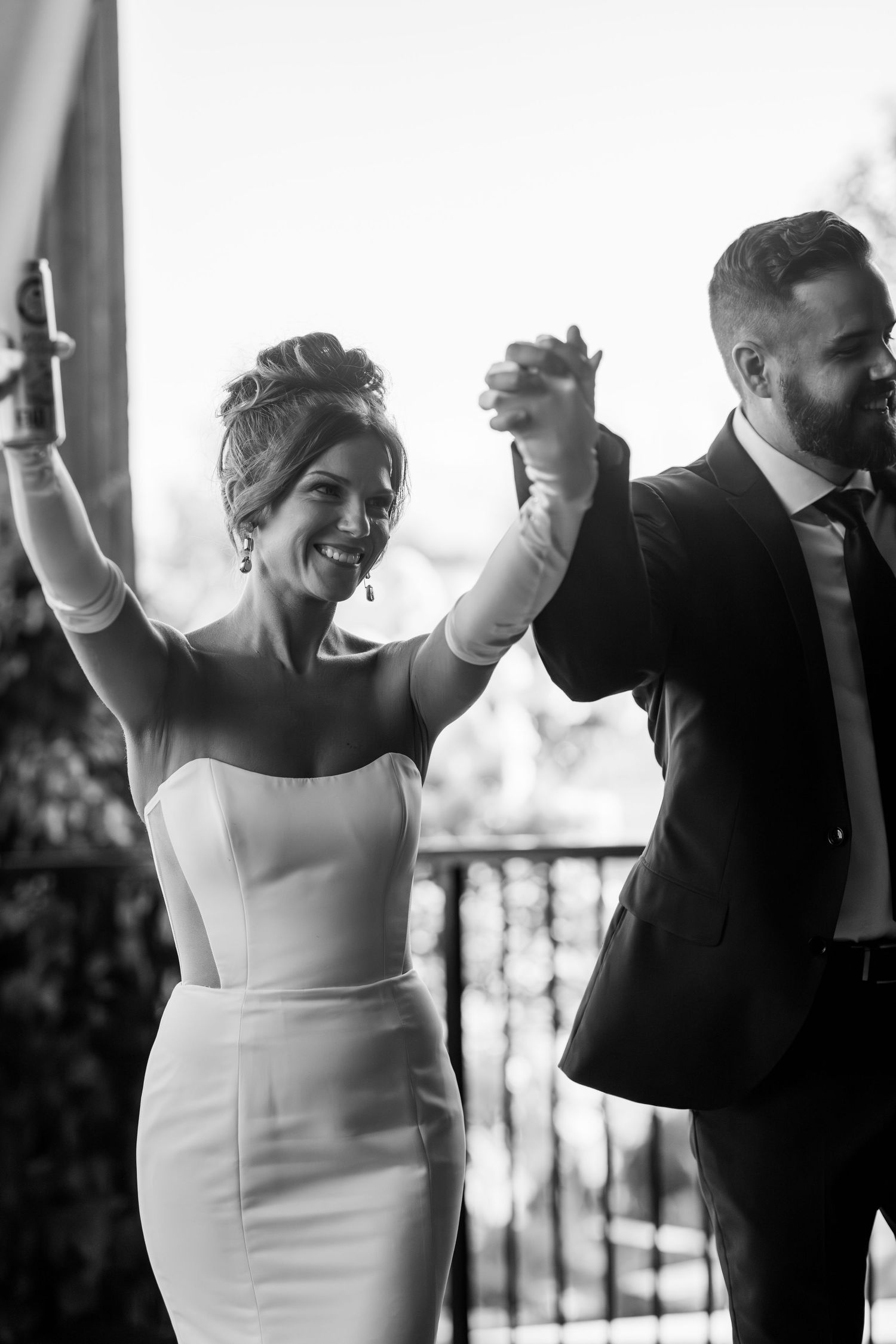 Black and white photo of joyful couple celebrating with raised hands during wedding ceremony.