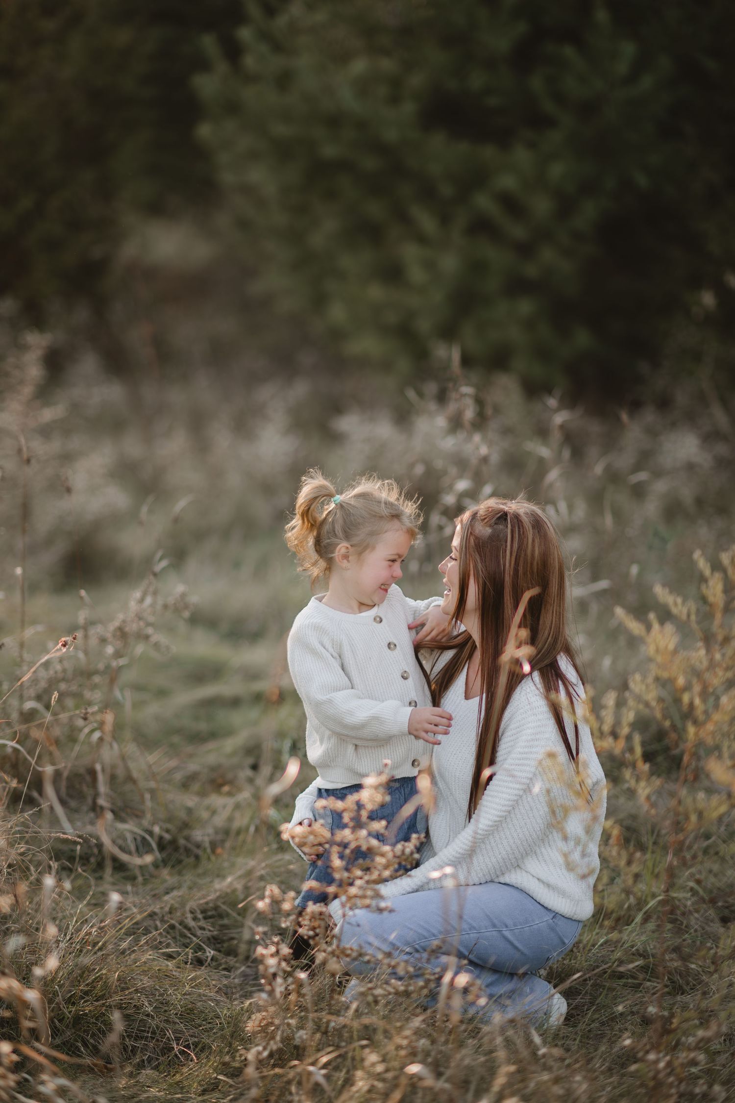 Children sitting together in tall grass during golden hour.