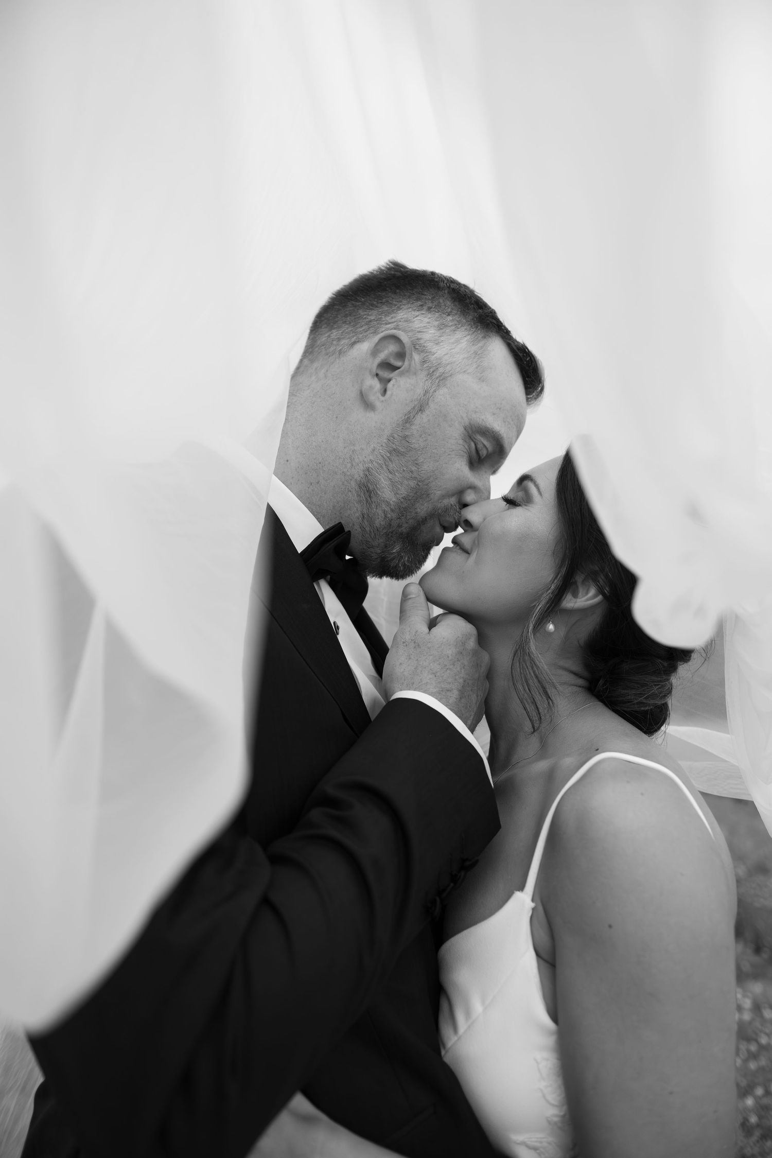 Black and white romantic portrait of wedding couple sharing intimate moment.