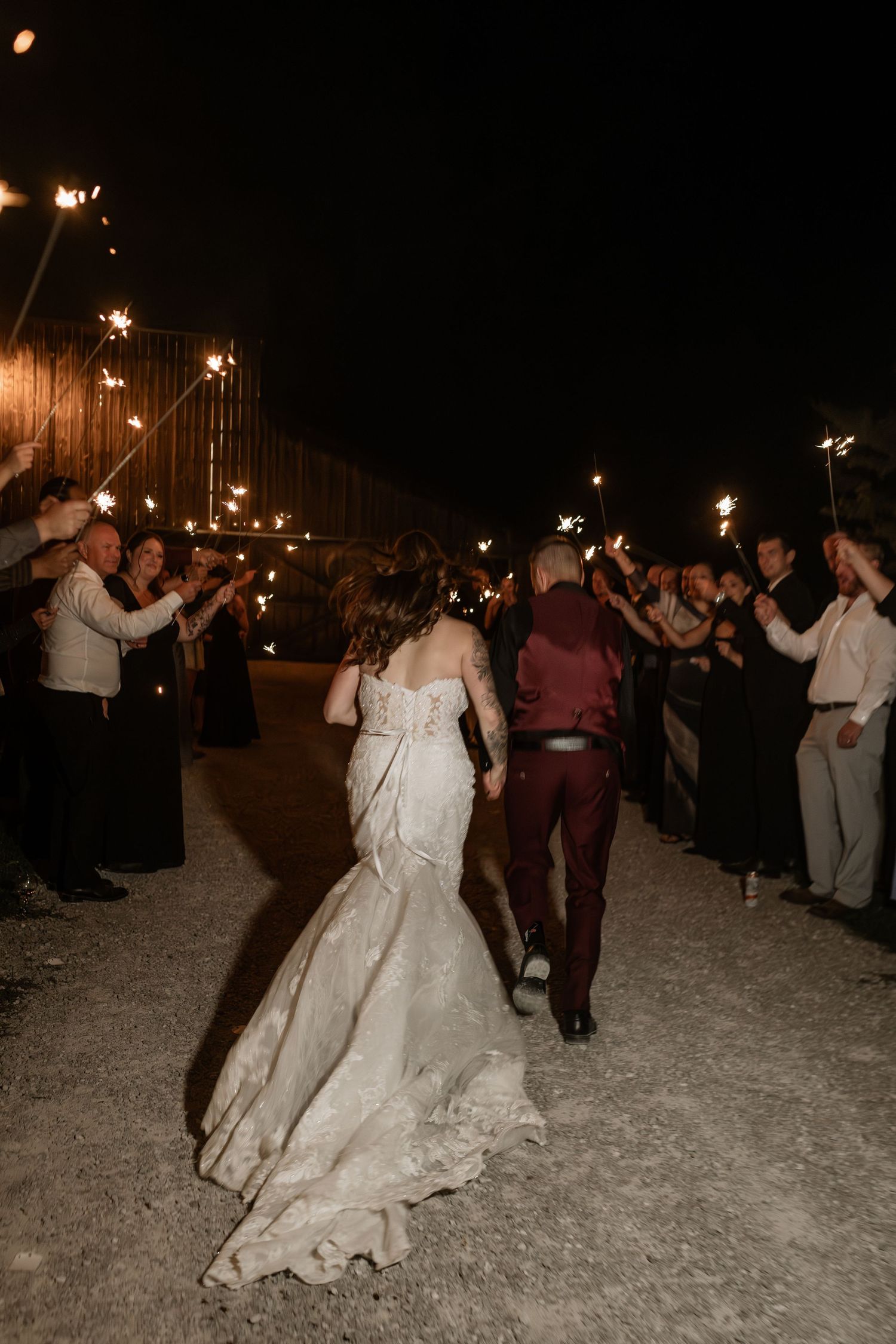 Couple dances under string lights during evening wedding reception outdoors.