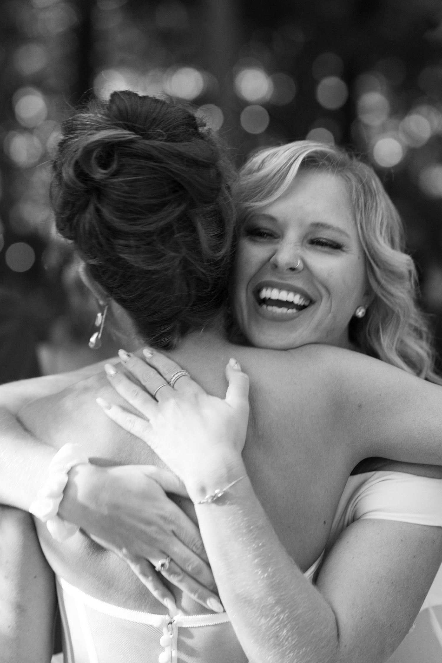 Candid black and white photo of wedding guests sharing a joyful embrace.