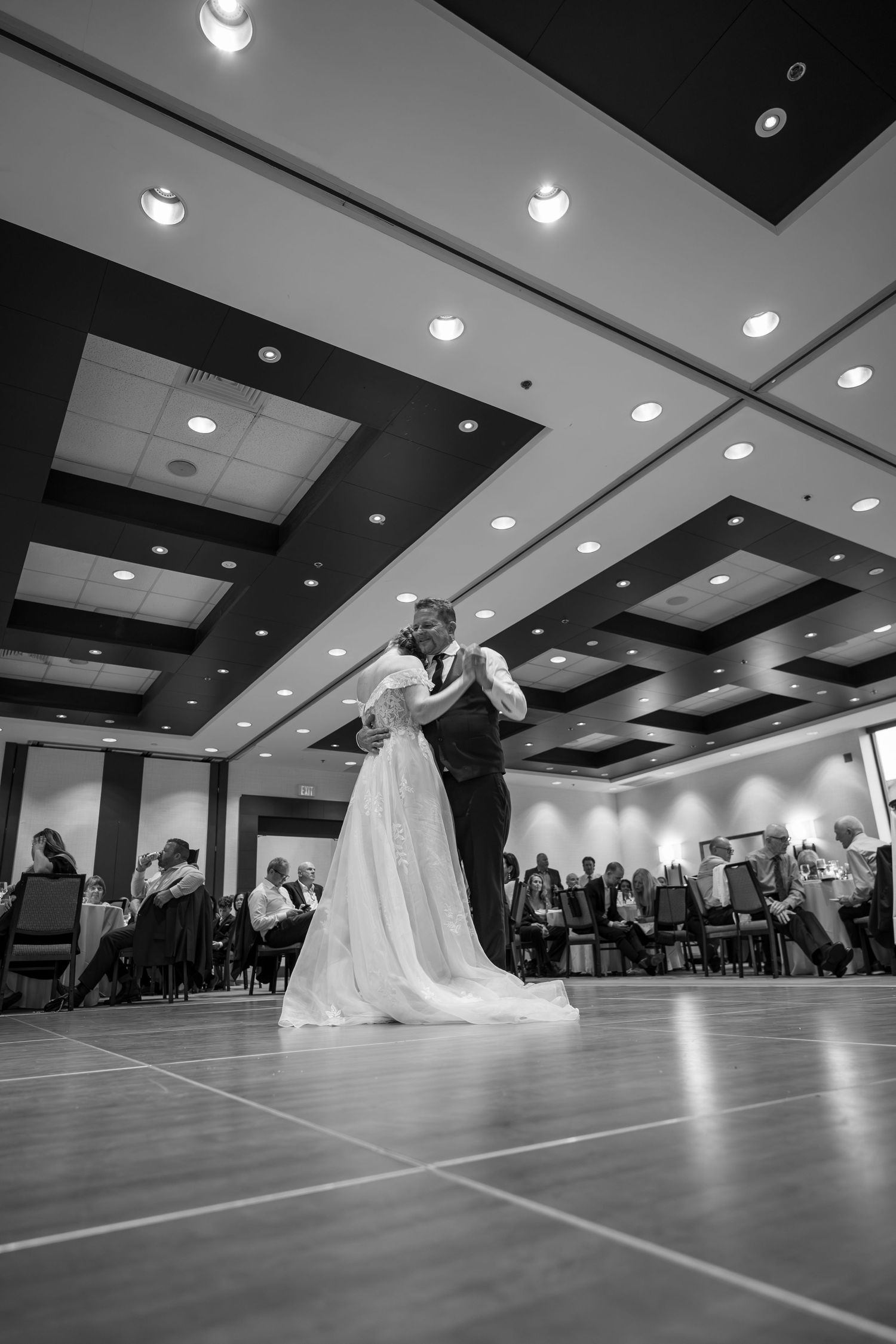 A dramatic black and white photo sequence of a wedding couple's dip dance move in a ballroom setting.
