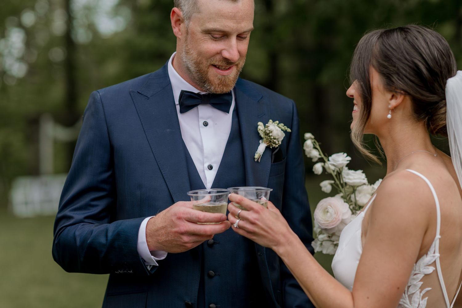Wedding couple shares intimate moment during outdoor ceremony with natural backdrop.