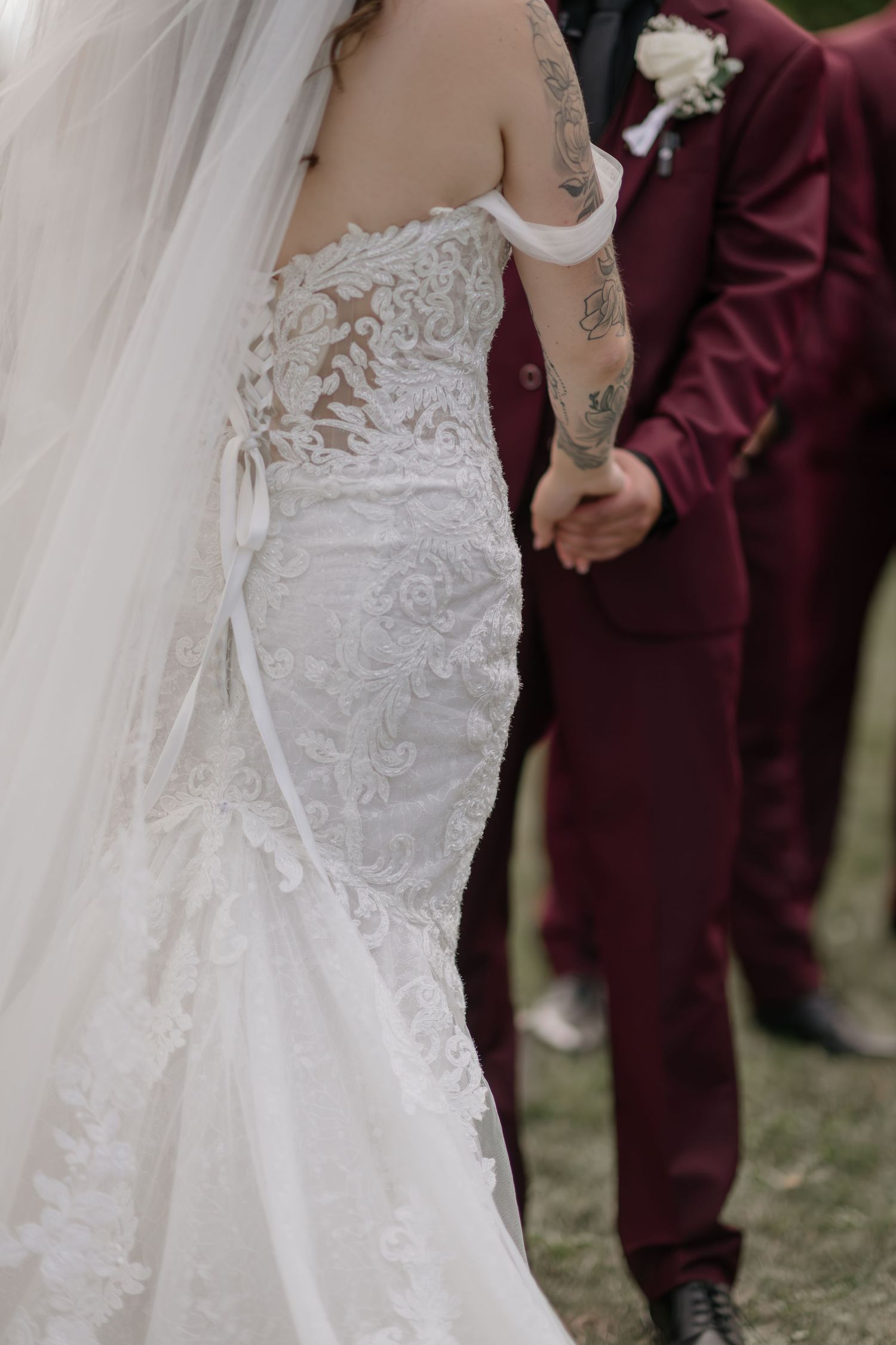 Close-up details of an intricate lace wedding dress with flowing train.