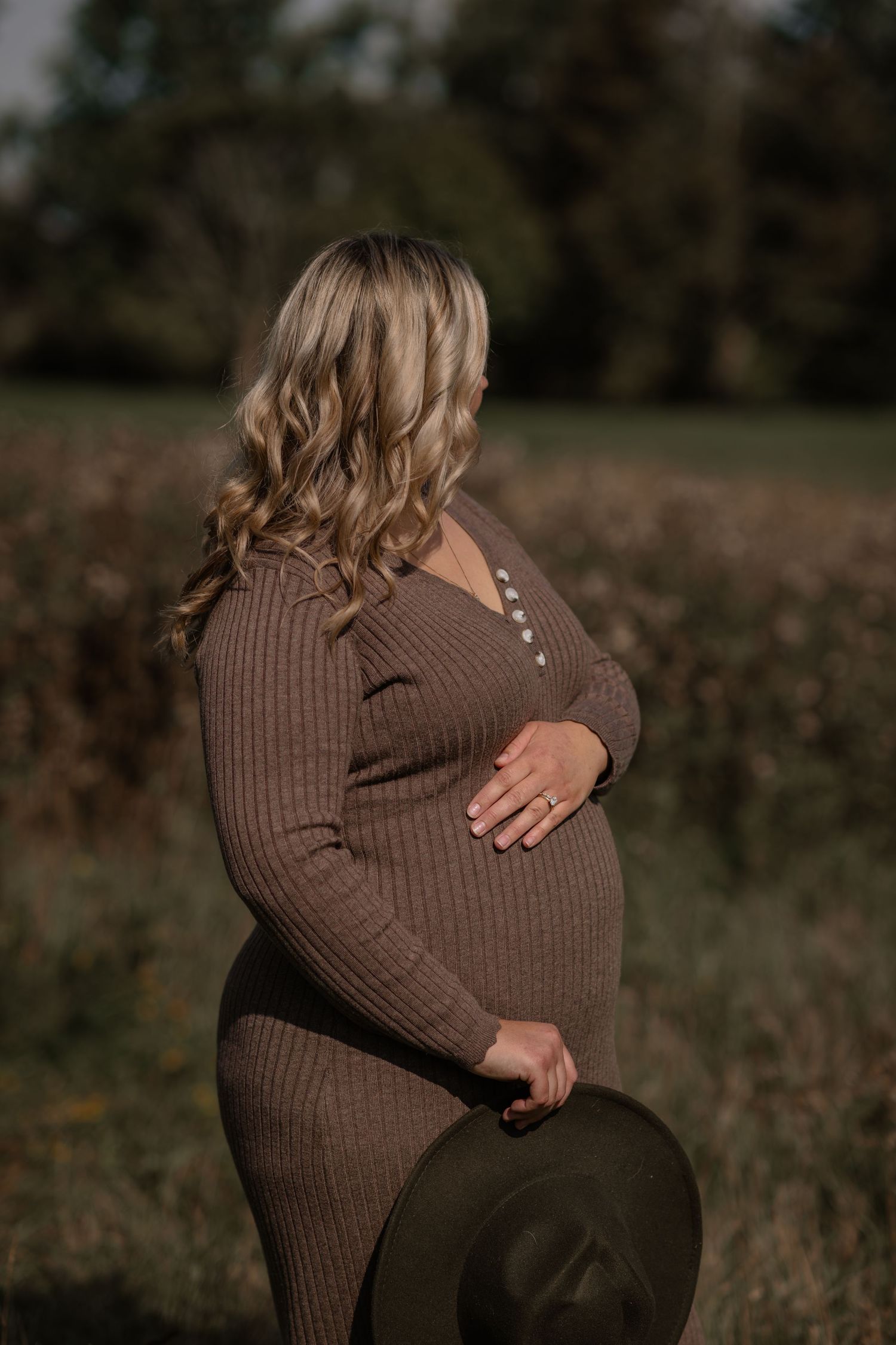 Close-up shots of a brown sweater-clad pregnant belly in natural outdoor lighting.