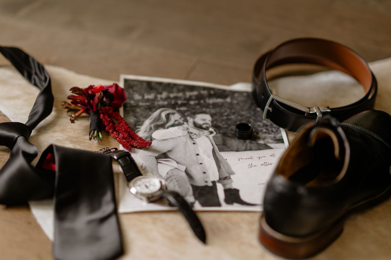 Wedding accessories including shoes, ties and jewelry arranged on wooden surface.