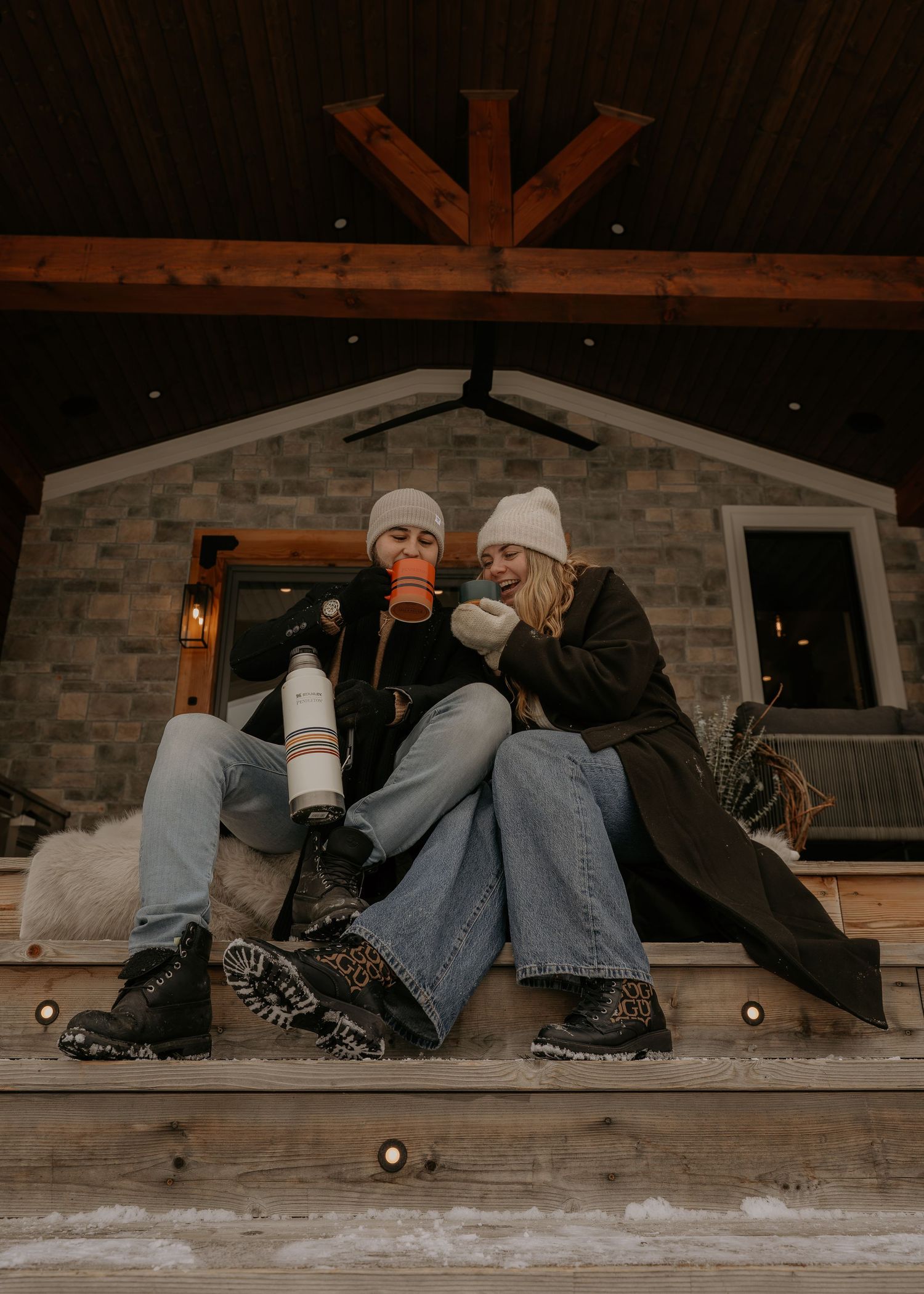 Two people relax on a snowy rooftop during winter evening.