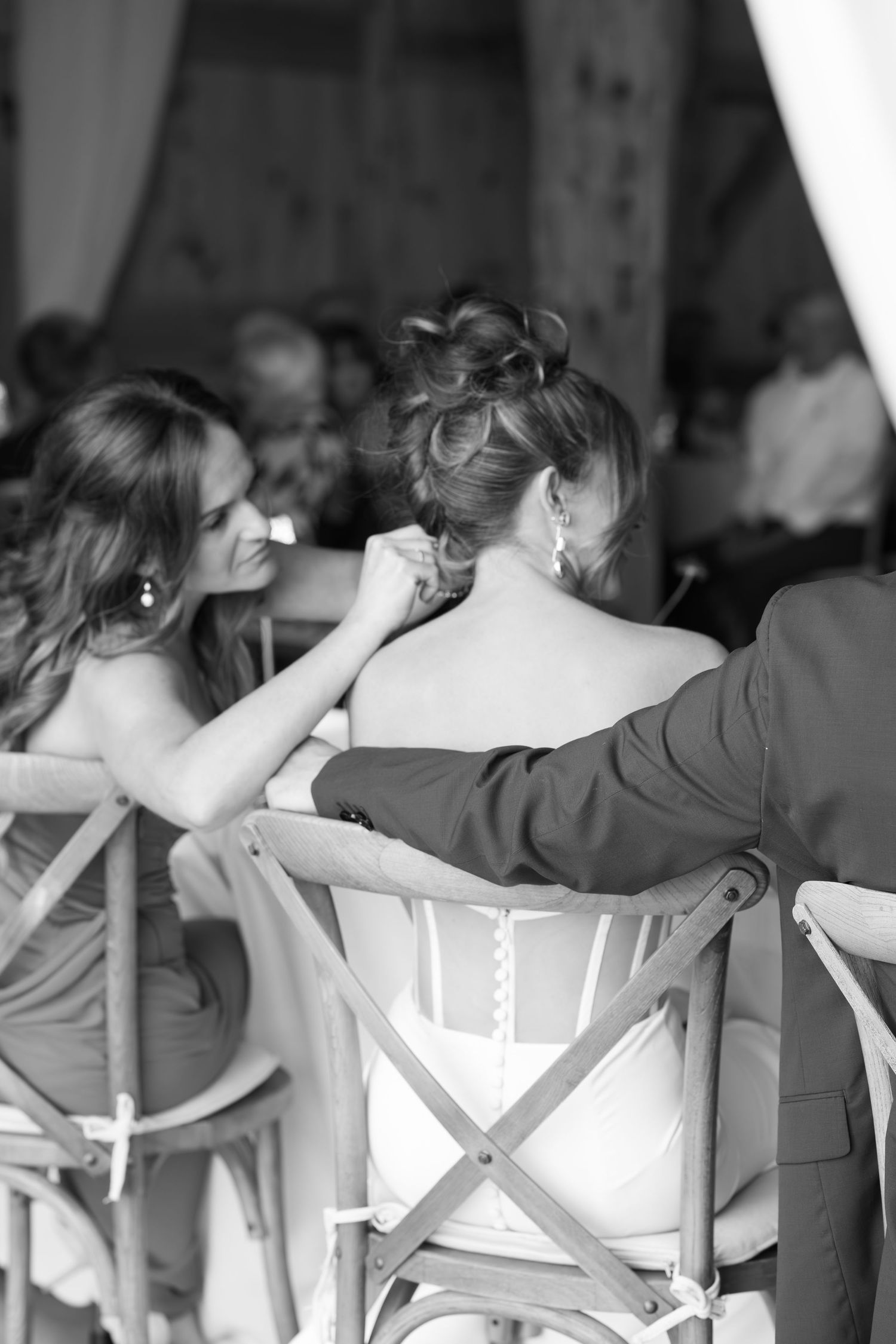 Black and white photo showing wedding reception guests seated in crossback chairs.