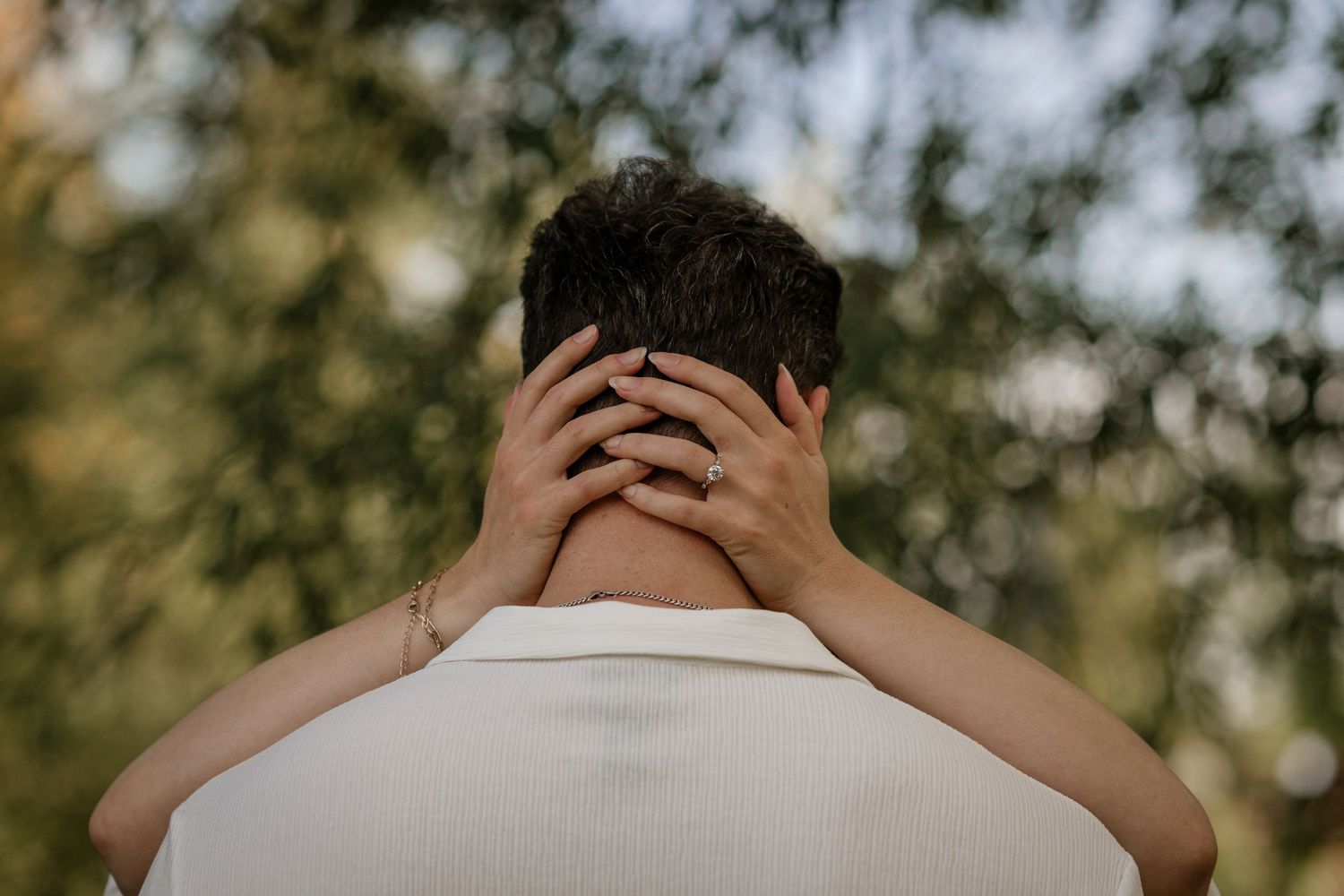 Intimate embrace captured in soft natural lighting outdoors.
