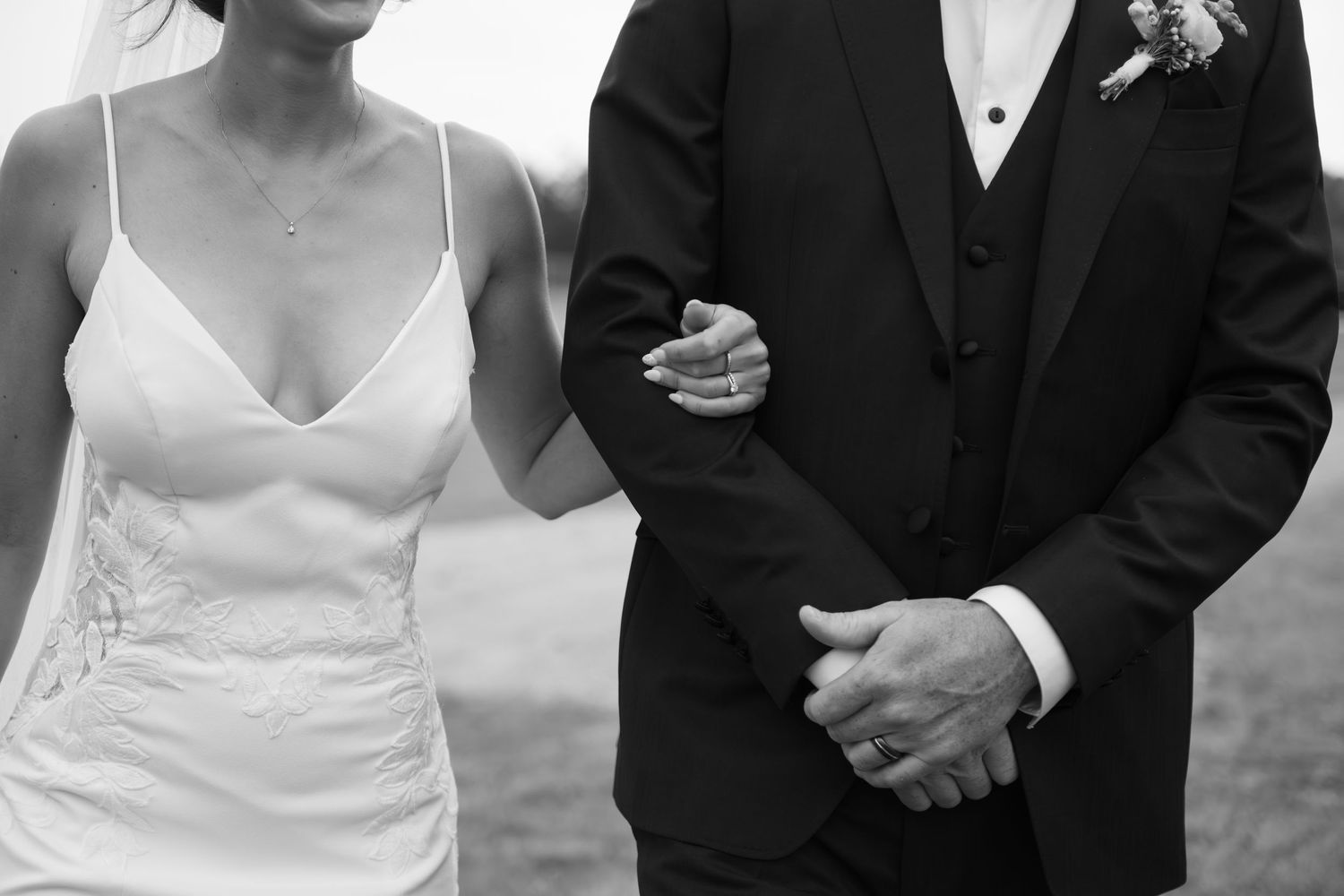 Elegant wedding party in formal attire stands together during outdoor celebration.