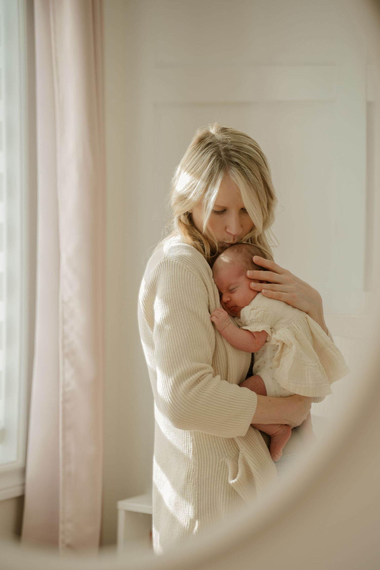 Gentle embrace in soft window light with cream knit sweater.