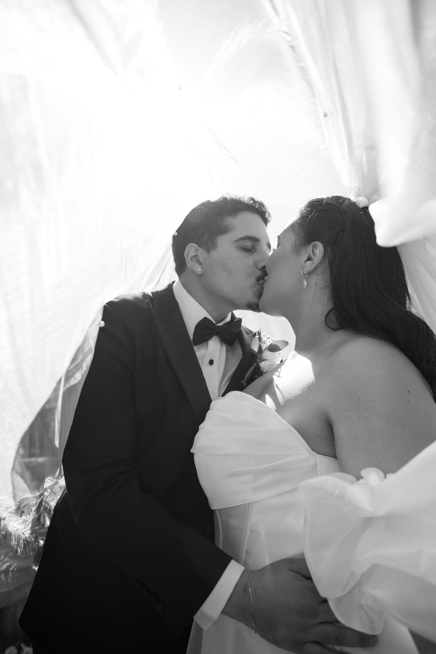 A romantic black and white wedding photo sequence showing the couple sharing tender kisses under a veil.