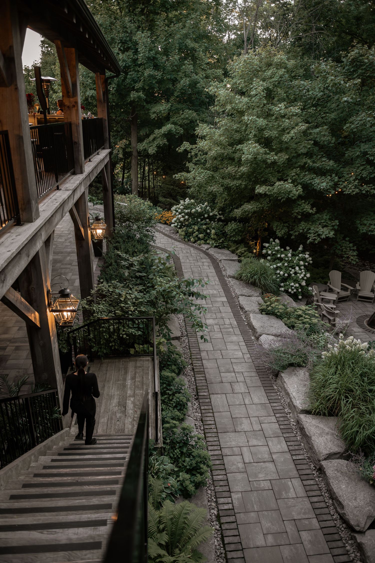 Stone pathway winding through a lush garden with wooden railings and steps in a peaceful setting.