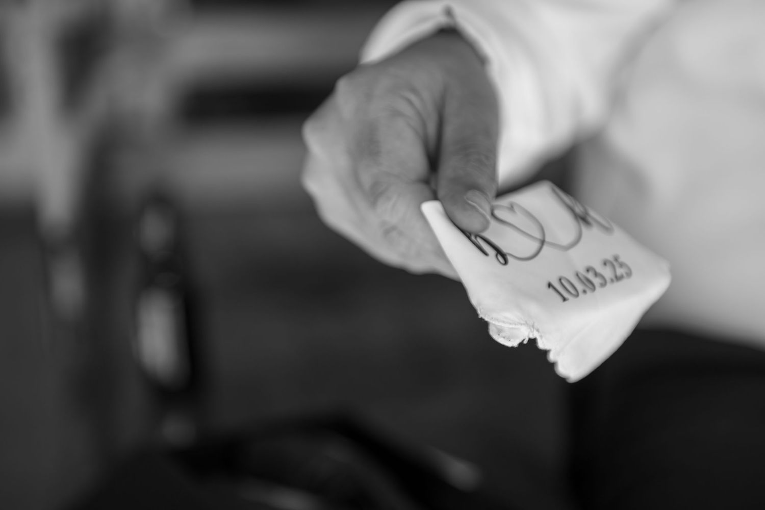 Black and white close-up of a hand holding a crumpled paper with handwriting visible.