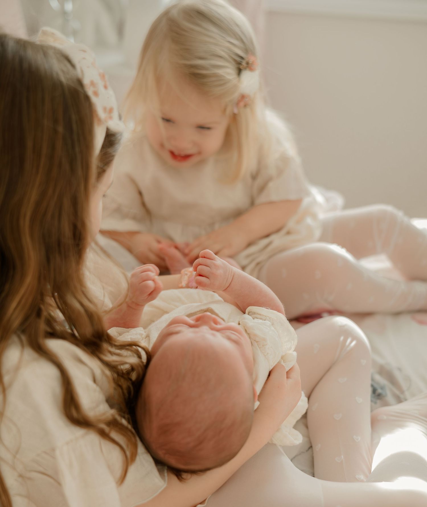 Tender moment between family members on bed in natural window light.