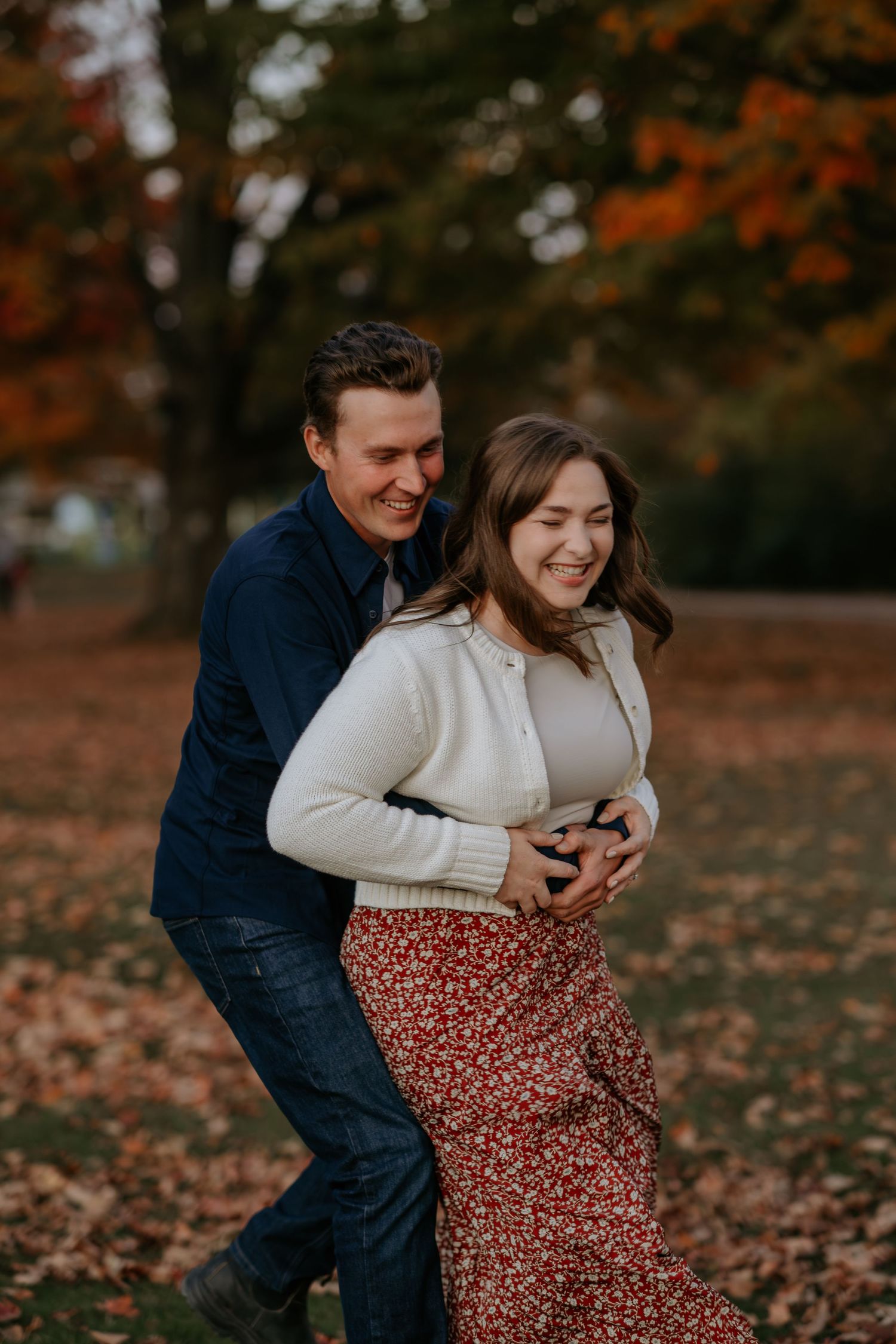 Couple sharing a joyful moment among fallen autumn leaves.