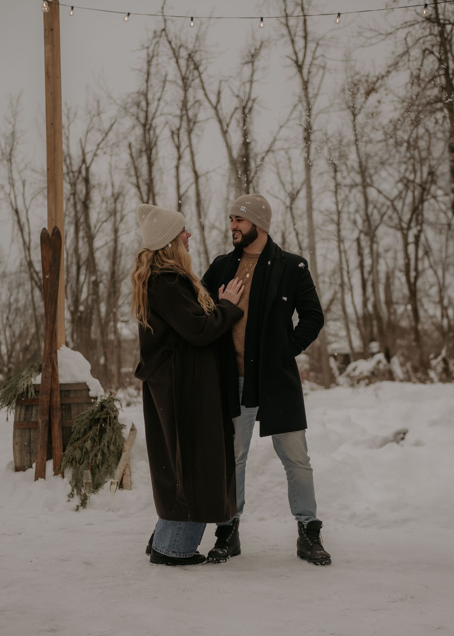 Two people walking through a snowy winter forest holding hands.